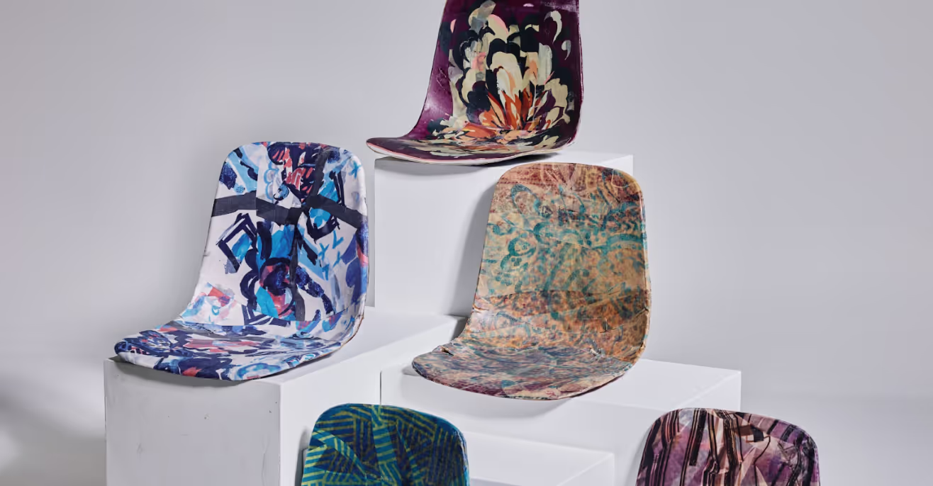 Six moulded chair shells with marbled and printed patterns displayed on white plinths