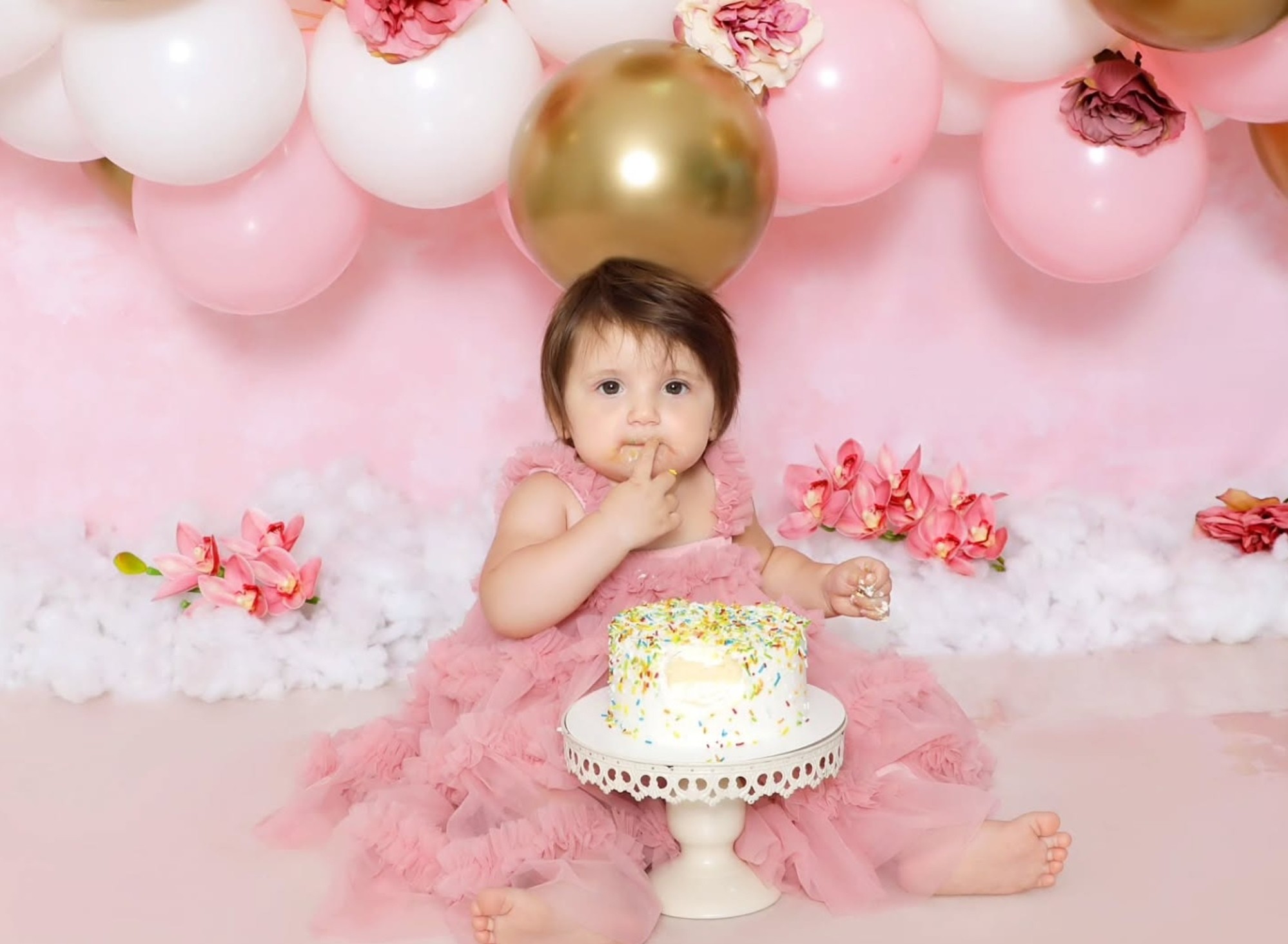 Baby enjoying a colorful smash cake with sprinkles at Mahvin Photography in Dubai, capturing fun and messy moments beautifully.