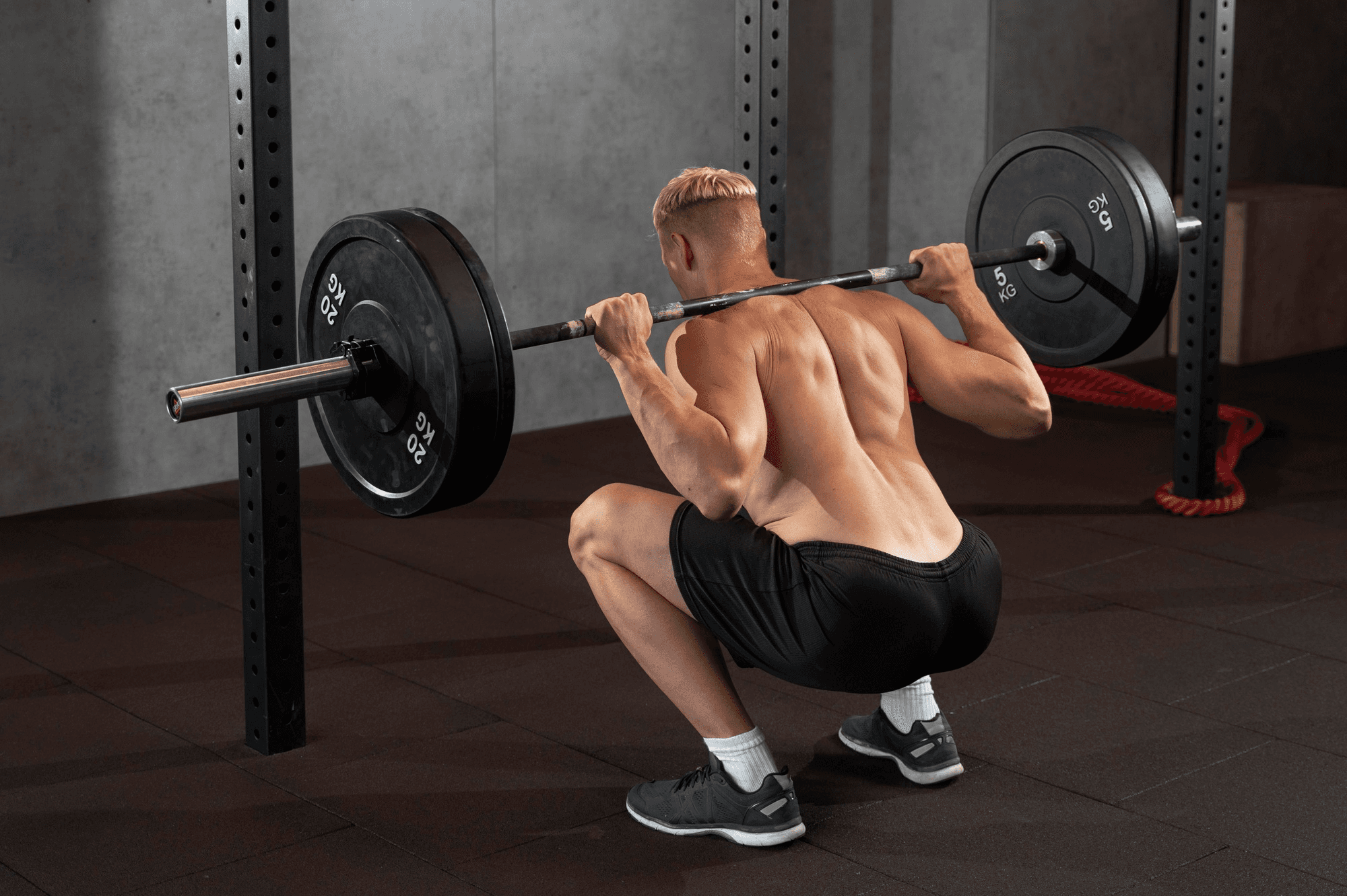 Man performs a barbell squat as part of his progressive resistance training.
