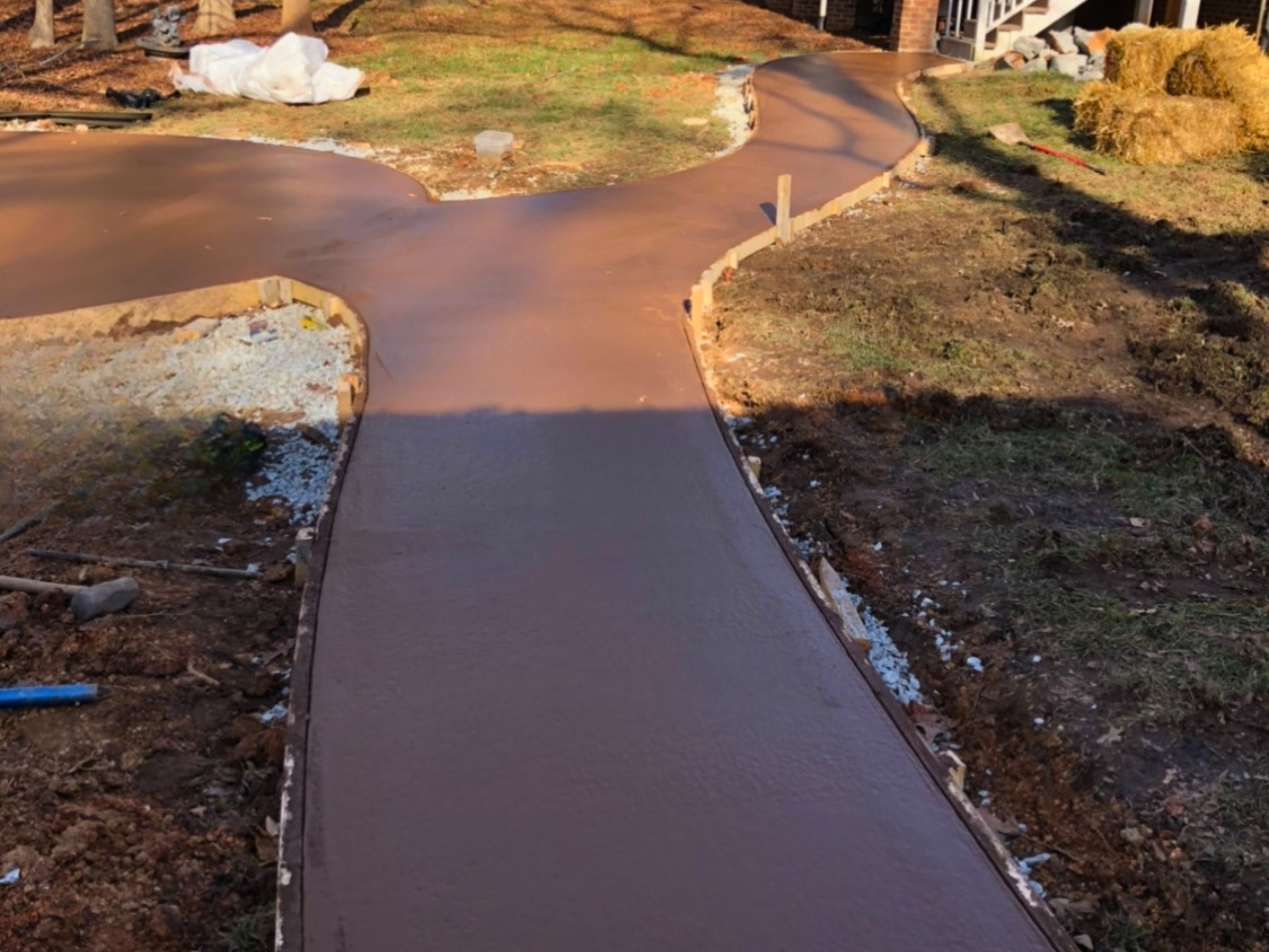 In‑progress view of the round concrete fire pit pad and curved walkway before landscaping is installed at a residential home in Durham, North Carolina.