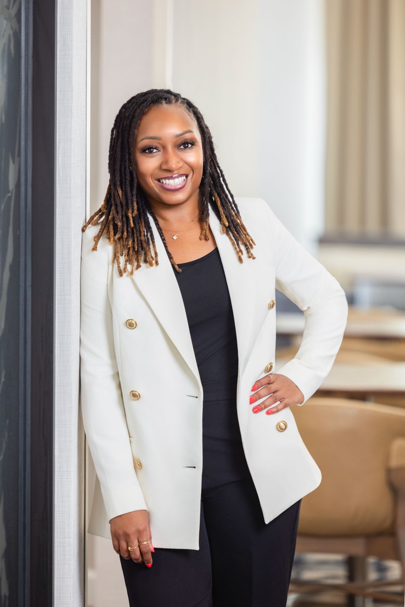 Dr. Jessica Saulsberry standing in a white blazer and black outfit in a professional indoor setting.