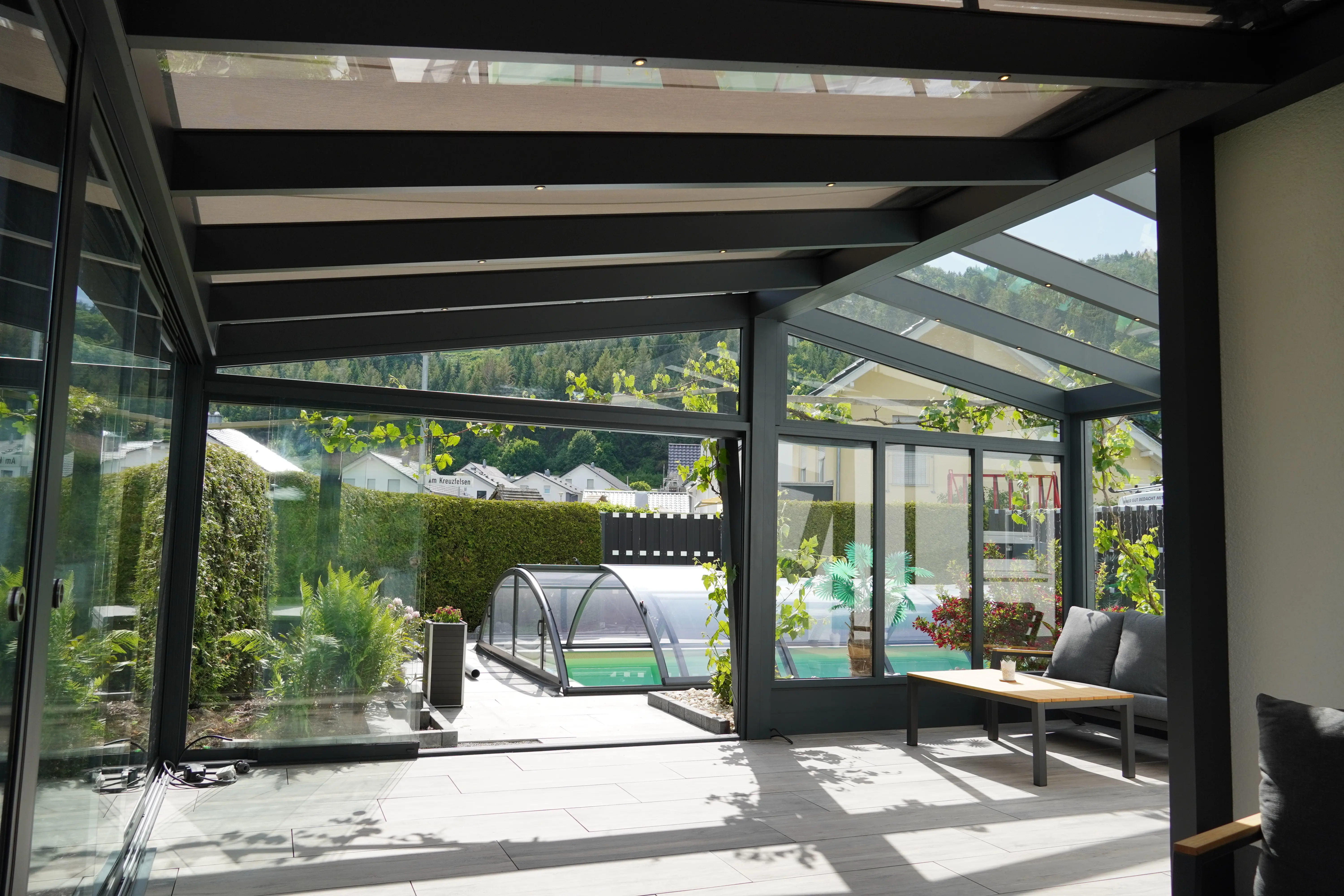 Verglaster Sommergarten mit Glasdach und Blick auf den Pool