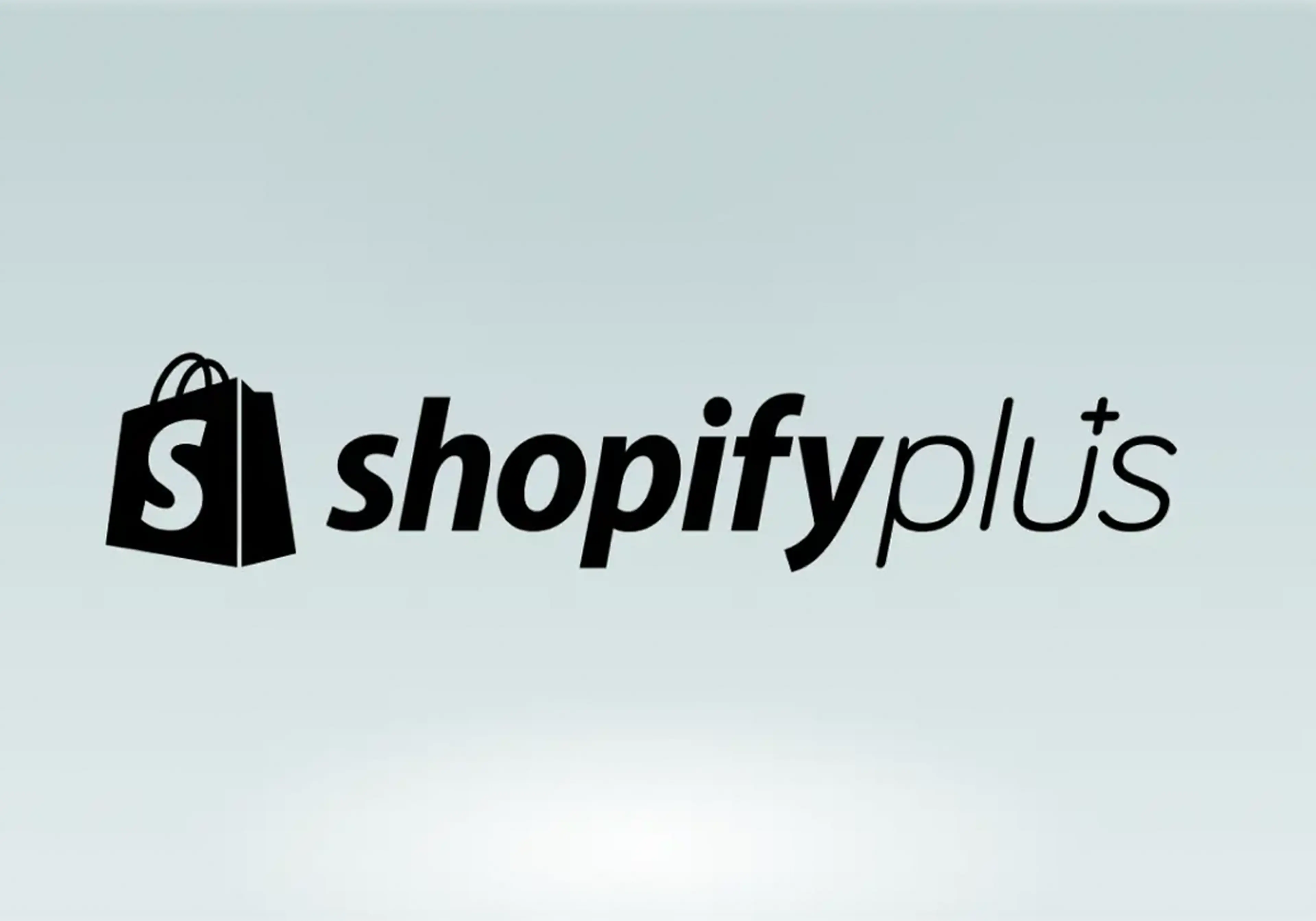 Shopify Plus logo, black shopping bag icon with white "S" next to the text "shopify plus" on a light gradient background | IDIGIU