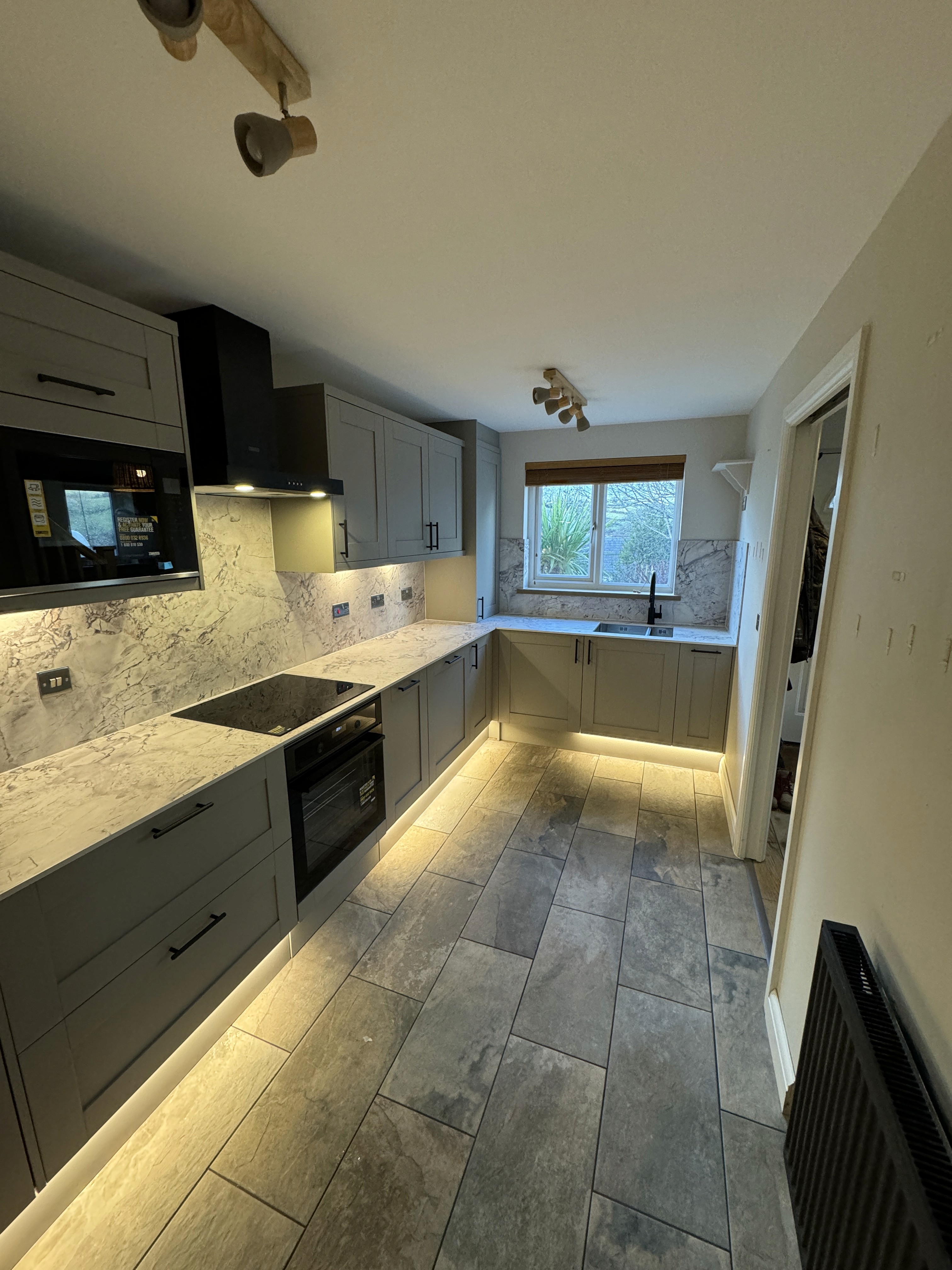 Modern indoor space with large glass doors, lush greenery, and a cozy seating area visible beyond.