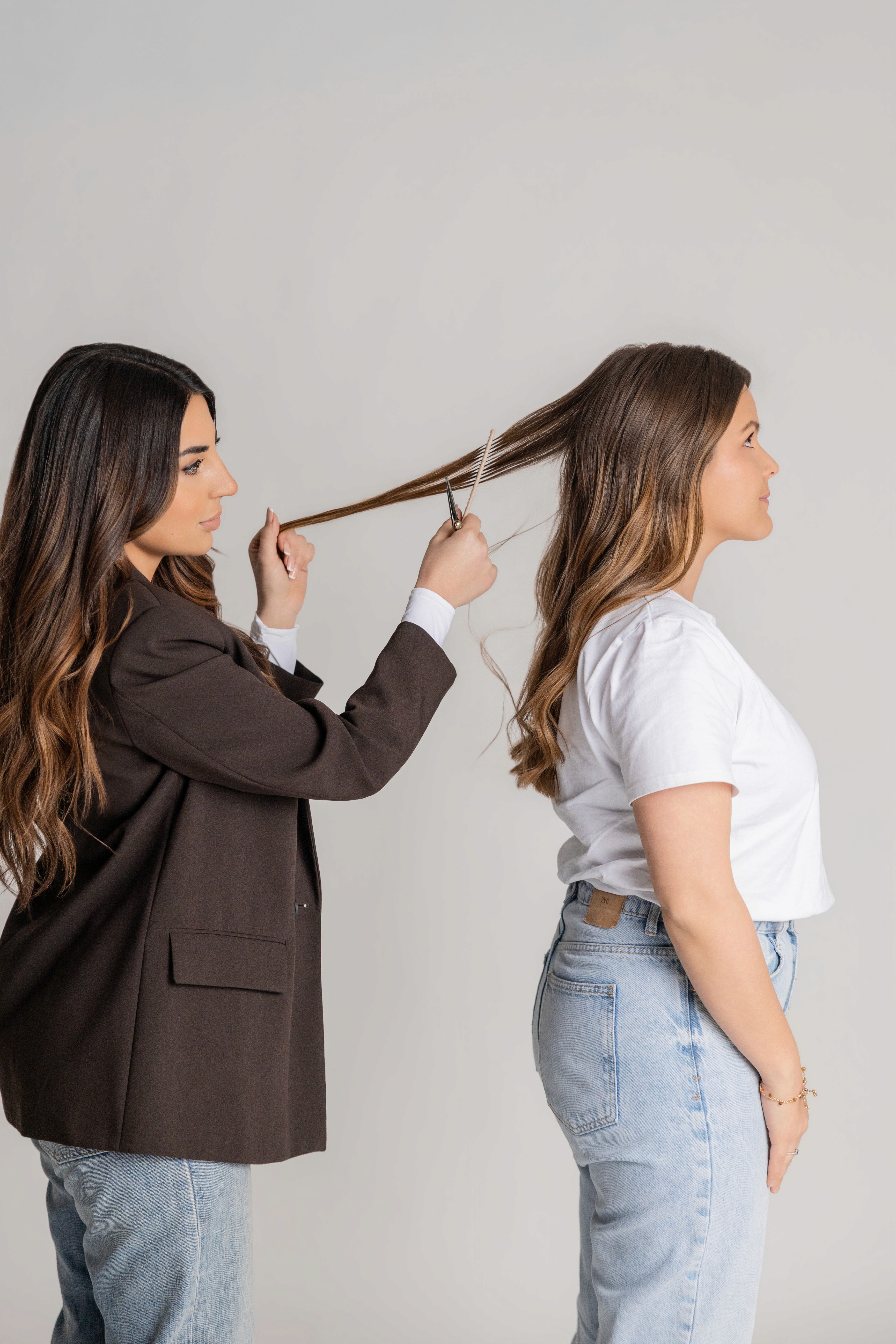 A serene and elegant spa space with wooden reclining chairs and white cushions. Golden sunlight filters through a cascading water feature, creating a peaceful atmosphere. Tropical plants and candles add to the relaxing ambiance.