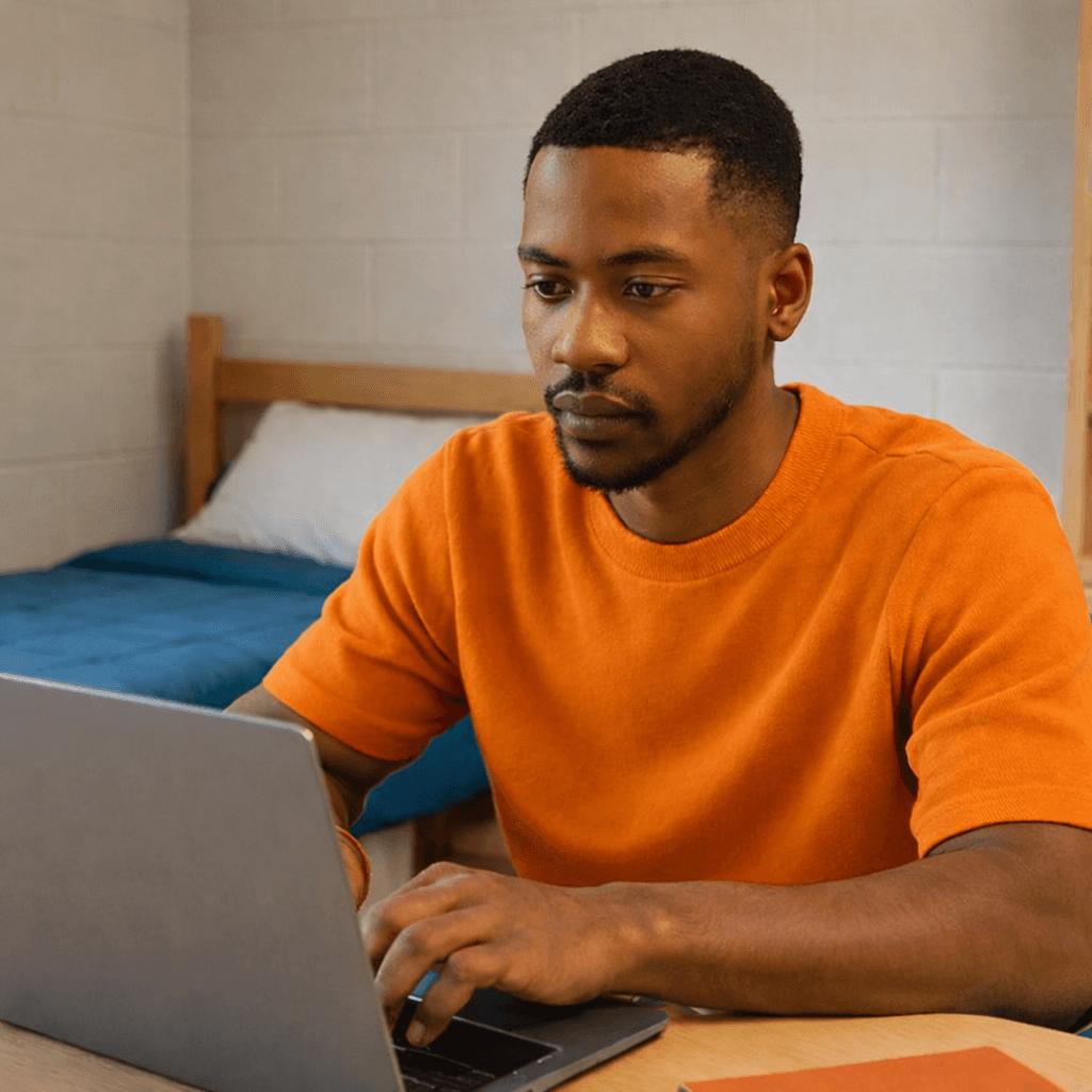 Student with brown shirt studying in his dorm