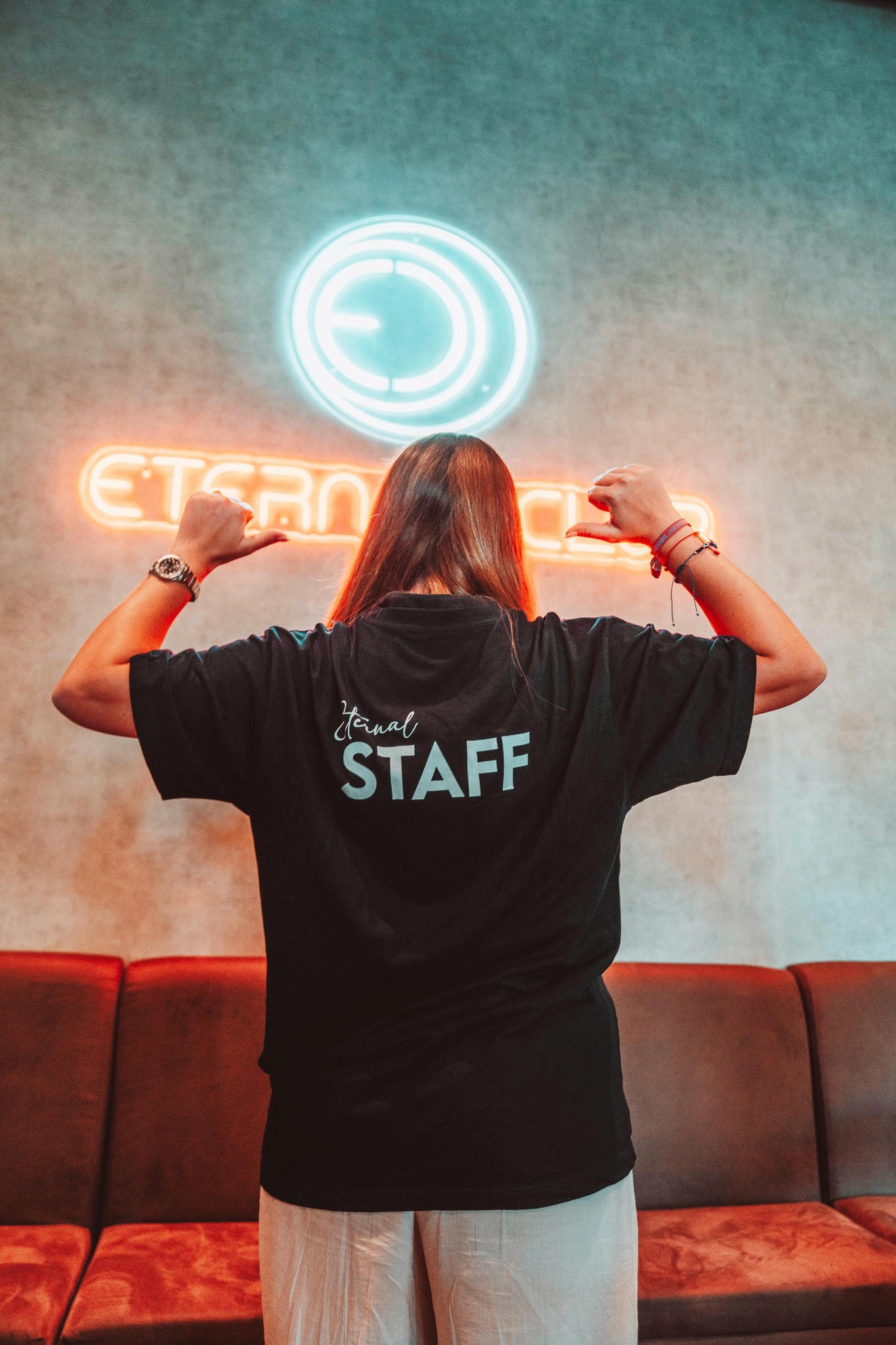 Miembro del staff posando con orgullo frente al logo de Eternal Club.