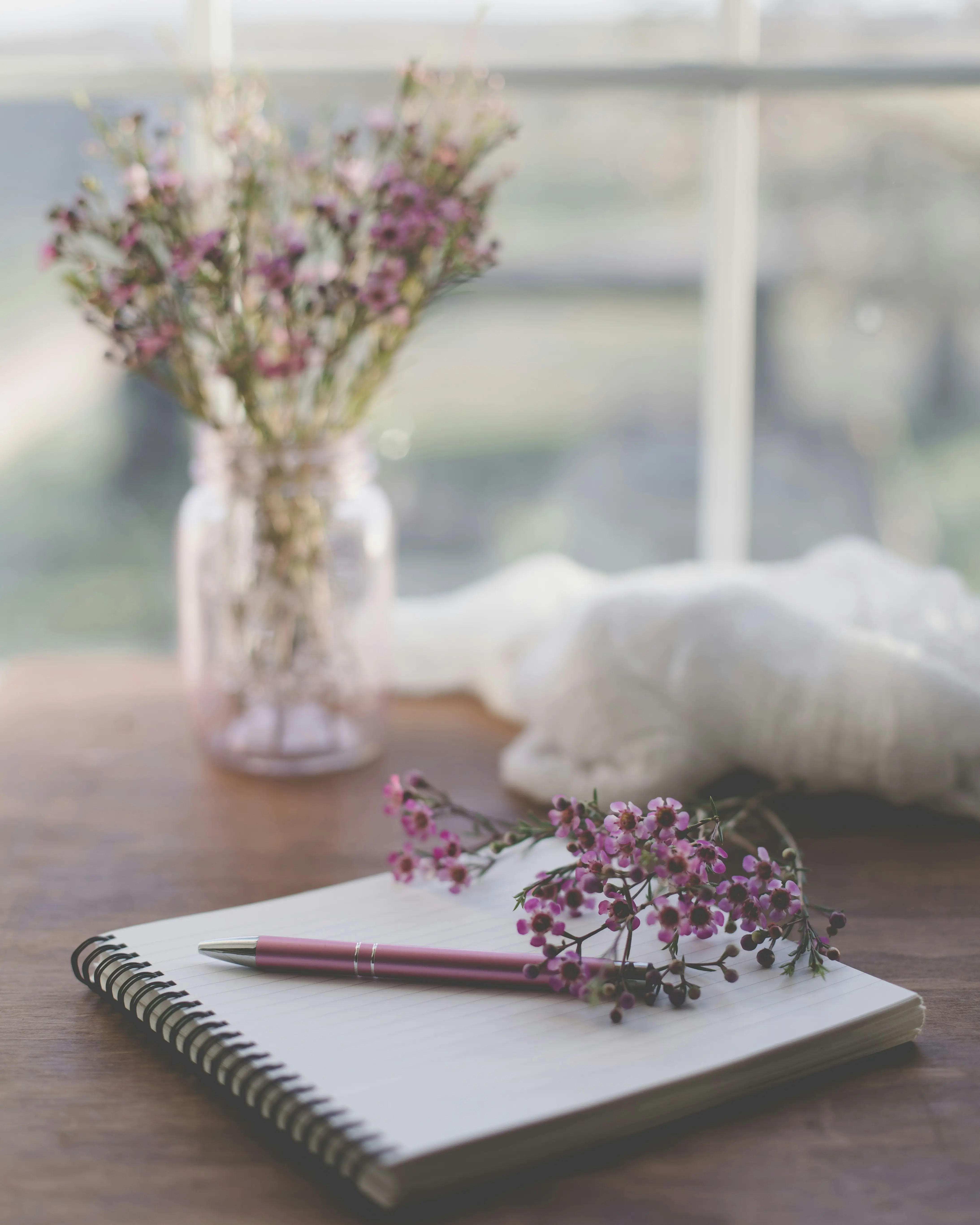 Fleurs délicatement posées sur un carnet d'écriture, symbole d'introspection et de cheminement intérieur