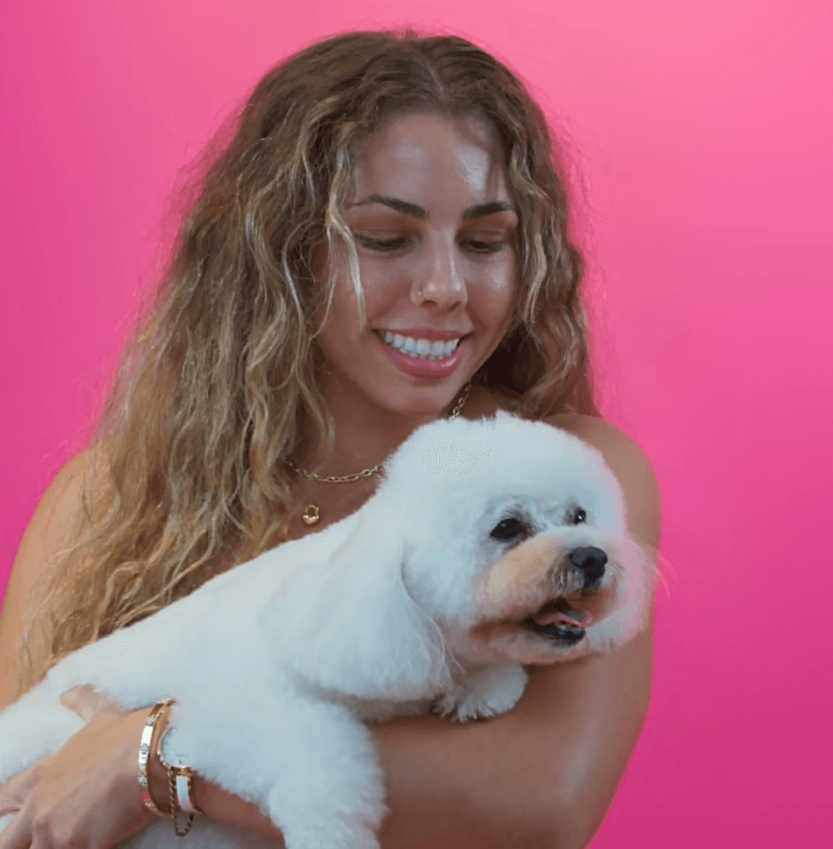 Smiling woman holding a freshly groomed white dog to express happiness, care, and confidence after a grooming session.