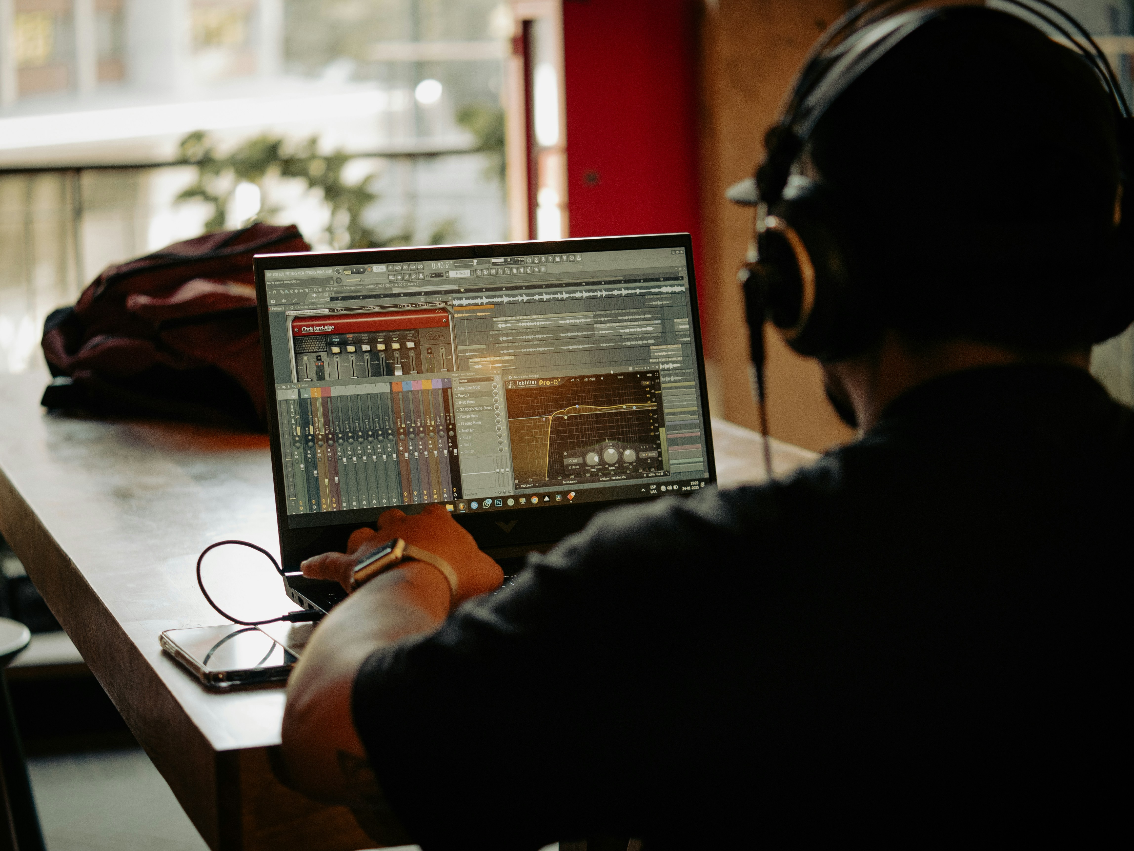 Person wearing headphones using laptop with audio software.