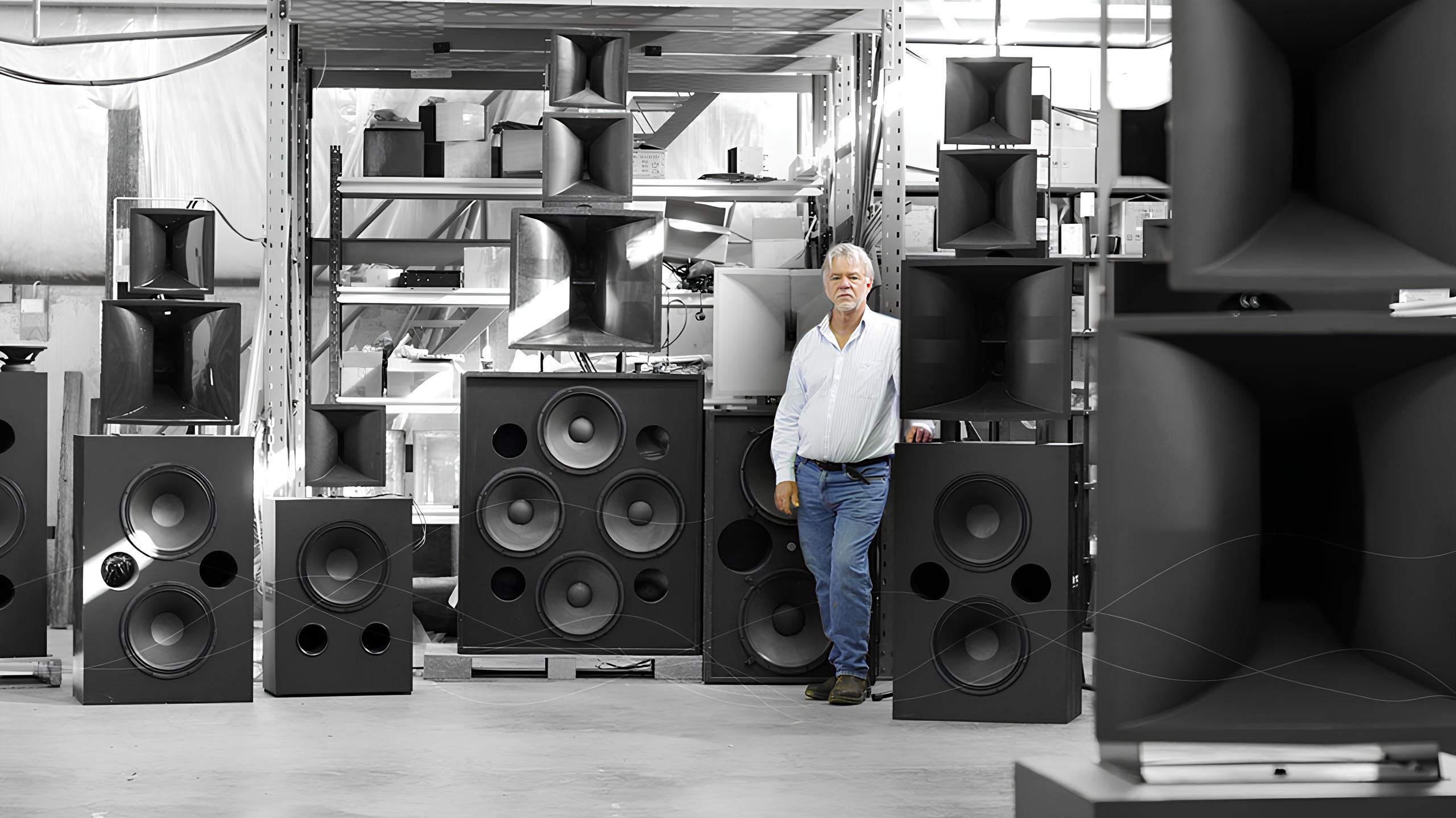 Man standing among large speakers and horns.
