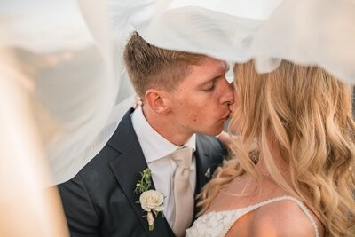 The newlyweds share a close-up kiss beneath the bride's veil.