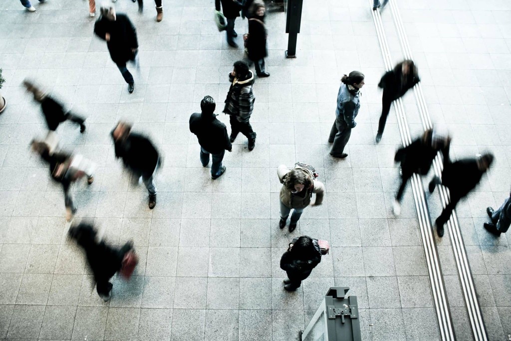 Busy urban scene with blurred people walking indoors.