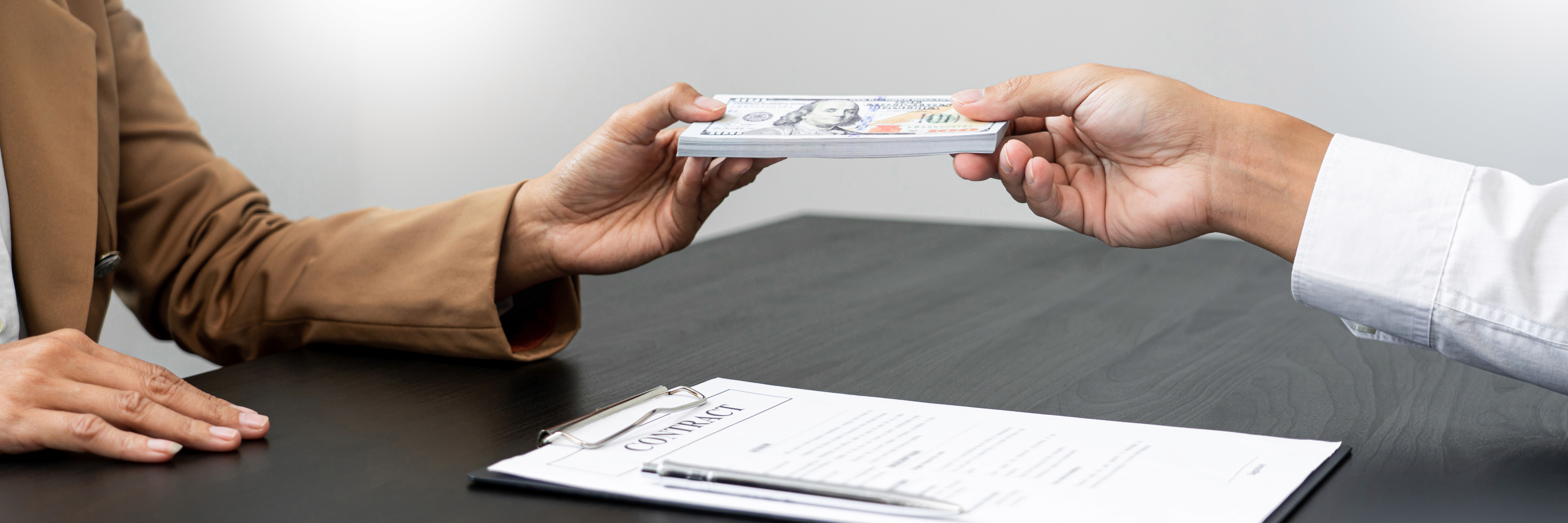 a group of people sitting around a table with laptops