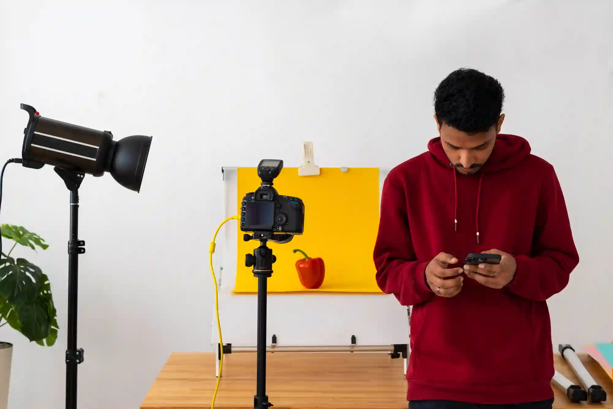 A content creator using professional lighting and a camera to film a healthy food blog featuring a pepper.