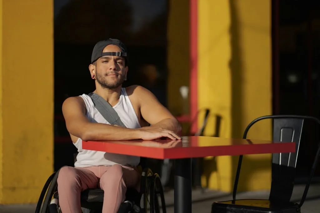 Wheelchair user sat at an outdoor table looking at the camera