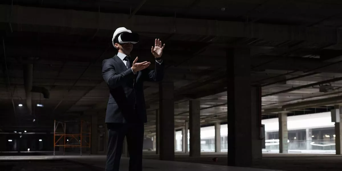 A man stands while two people sit at a table in an office setting, smiling and engaged in conversation. The mood is friendly and collaborative.