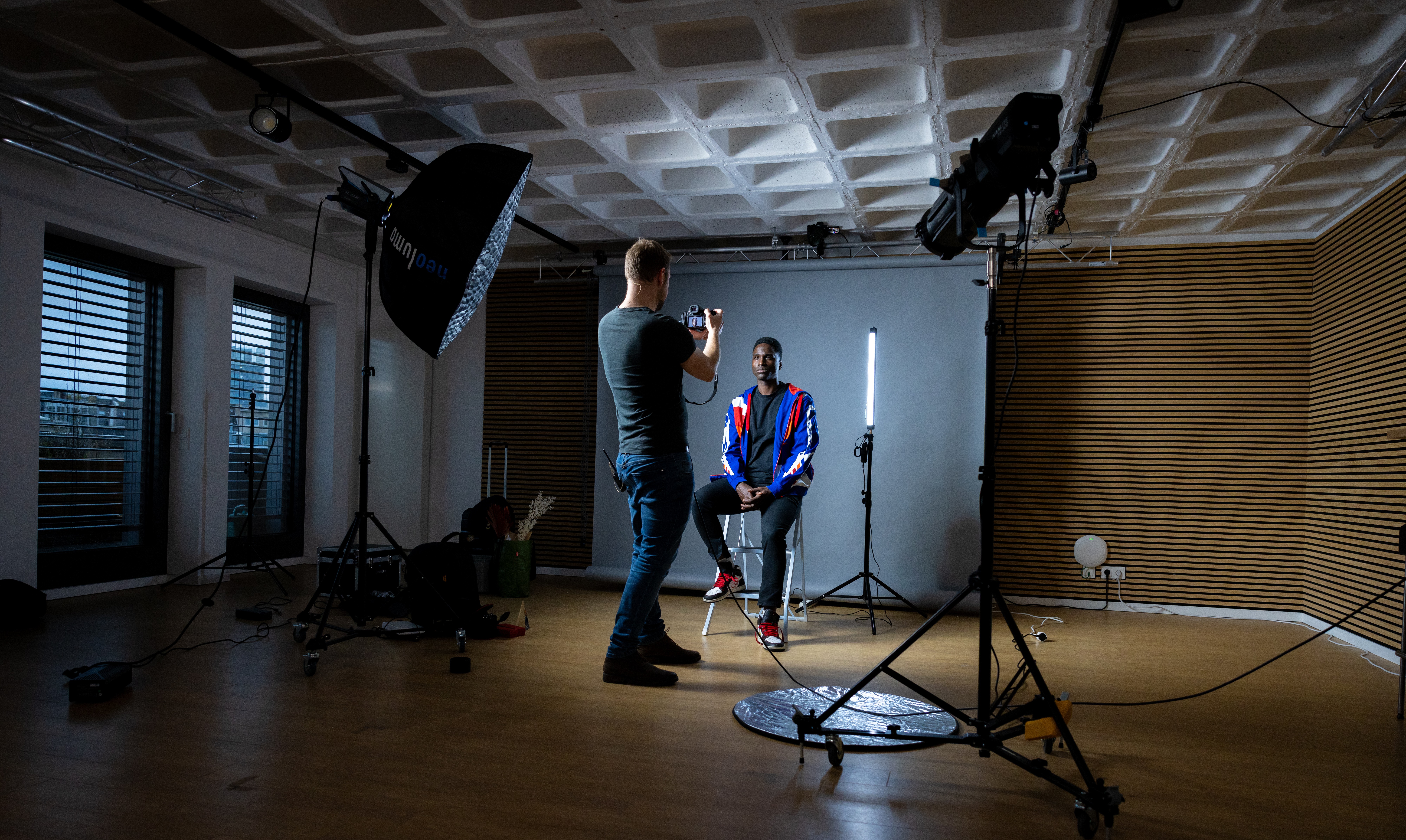 Fabian Grell fotografiert einen sitzenden Mann im Studio mit Softbox und Leuchtstab