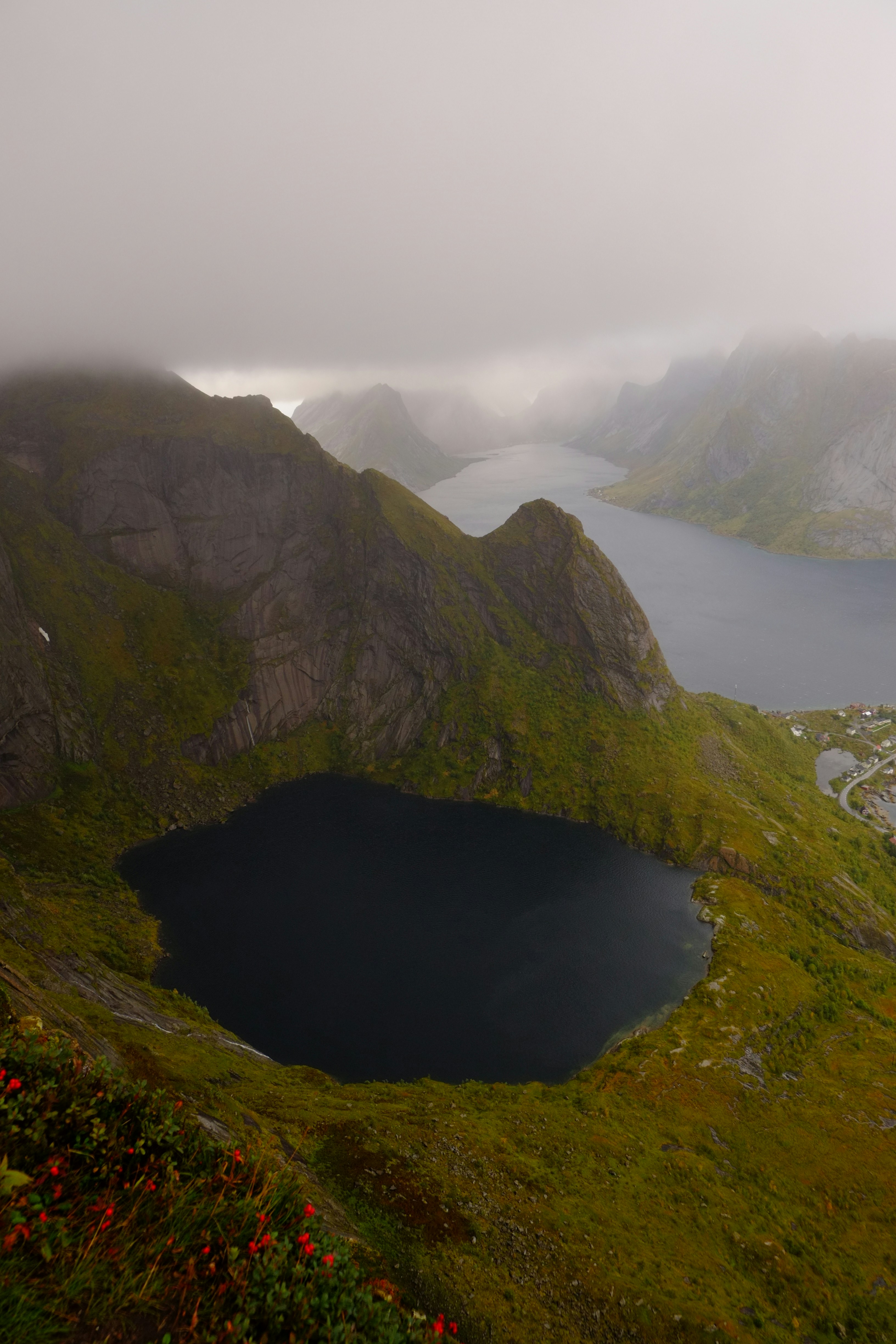 Misty mountains overlook dark lake and distant sea