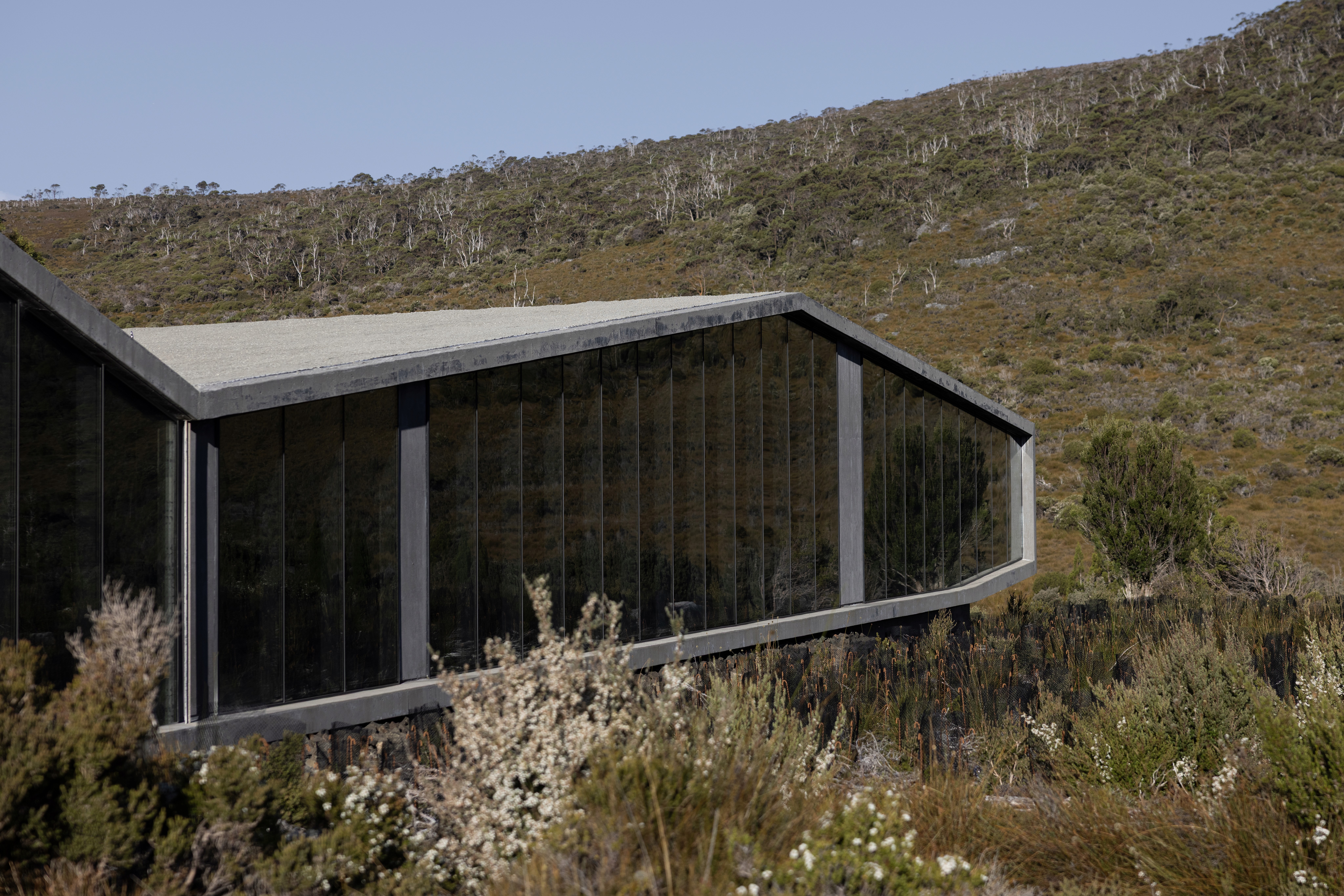 Captured from a low vantage point, the building’s sharp edges frame the wildness of the terrain, illustrating a design philosophy that prioritizes the identity of the place over the ego of the form.