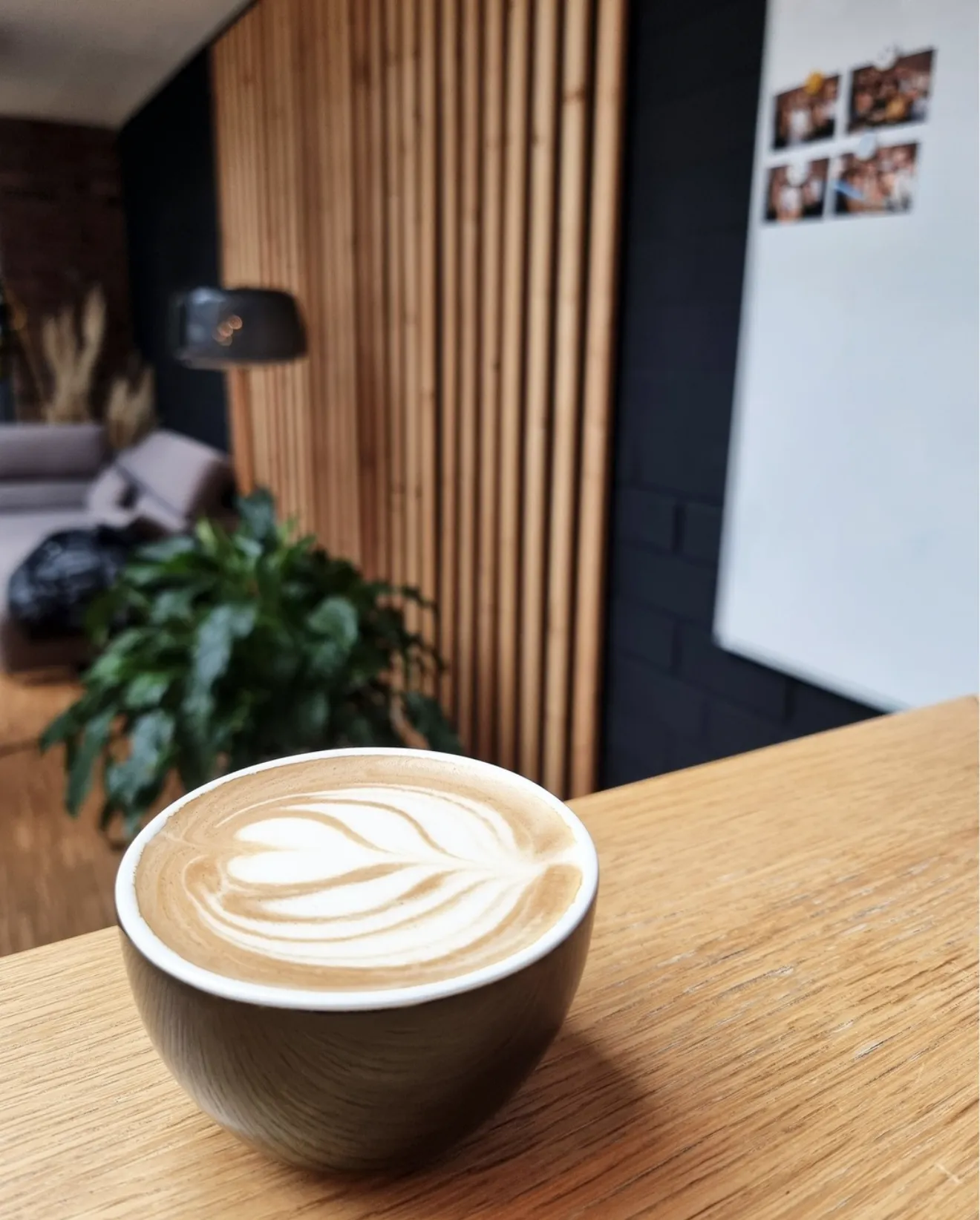 Latte mit Blatt-Latte-Art auf einem Holztisch in der Lounge des SnapNext-Büros