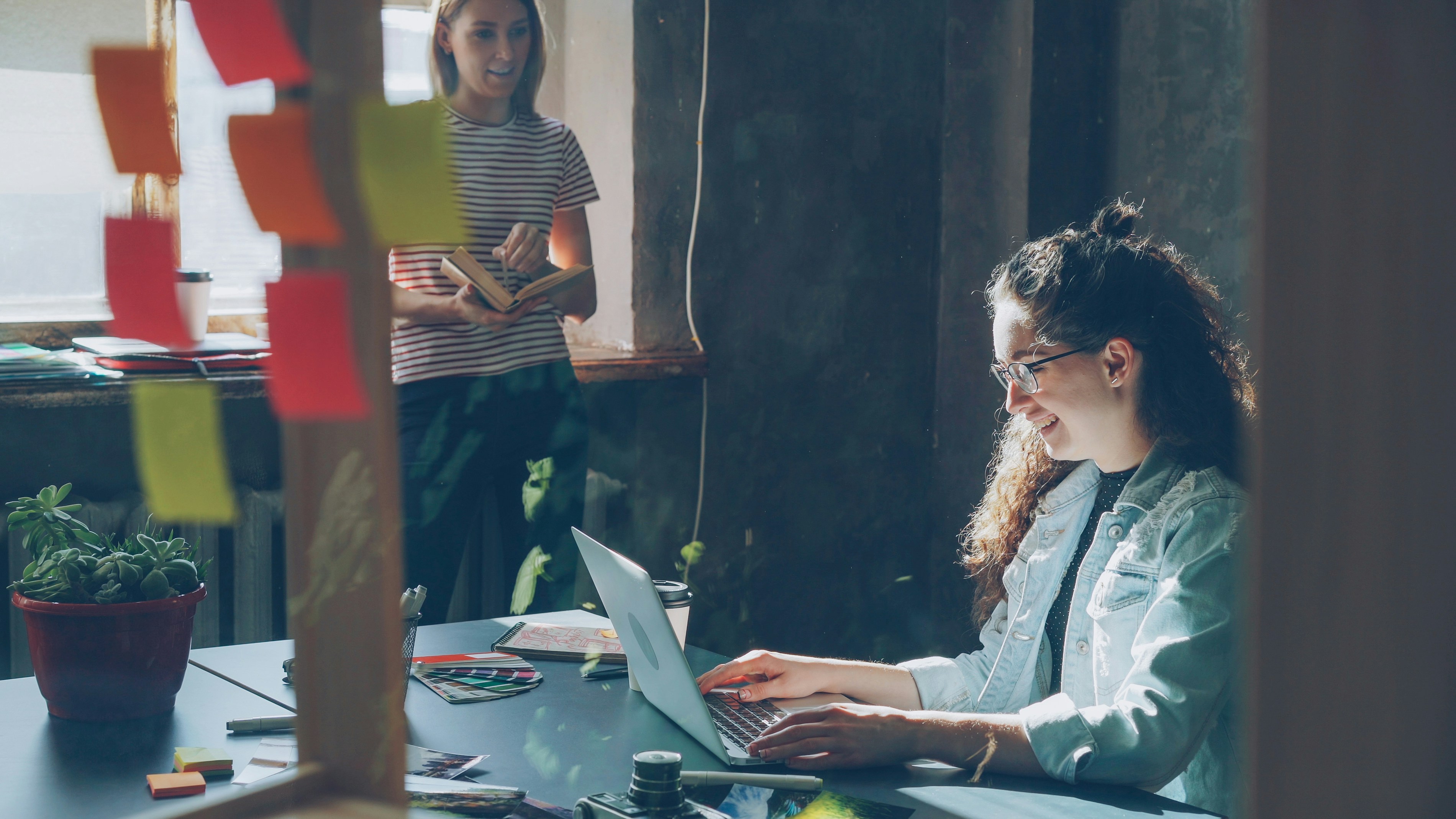 Two women work in a bright office setting.