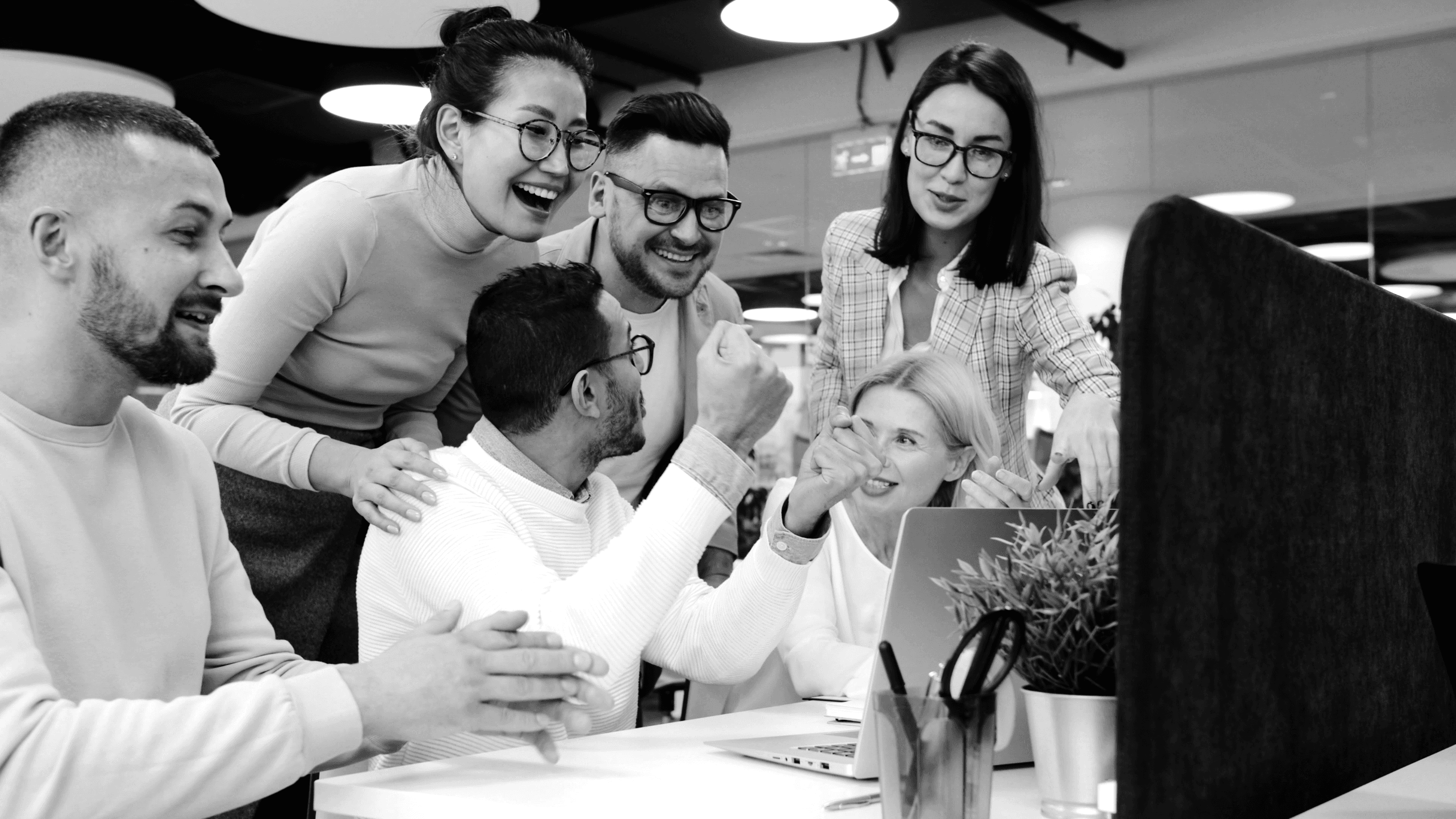 Diverse team celebrating success at office desk.