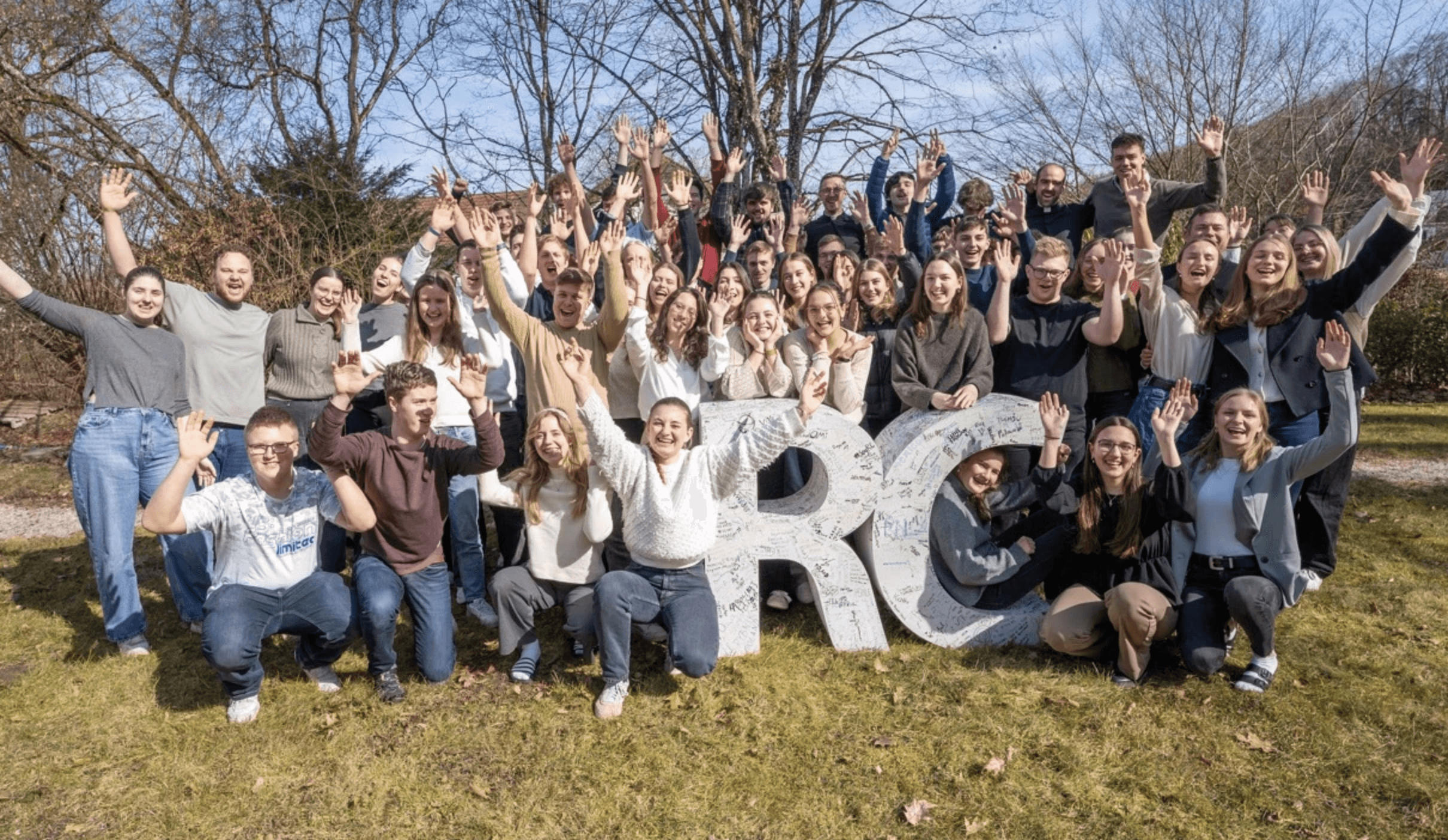 Eine Gruppe junger Leute steht im Freien um ein großes RC versammelt und jubelt