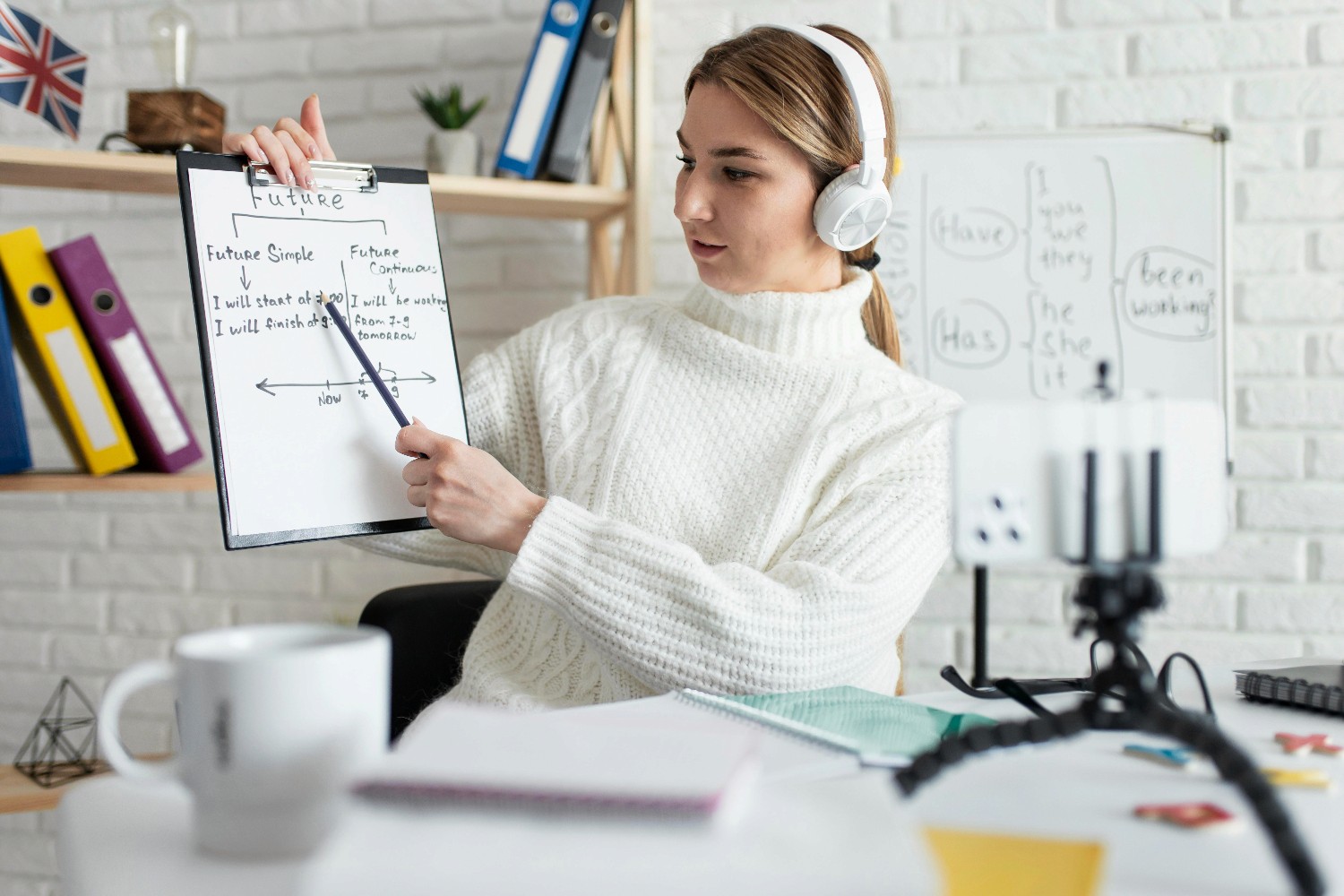 A woman seated at a desk holds a clipboard, appearing focused and engaged in her work.