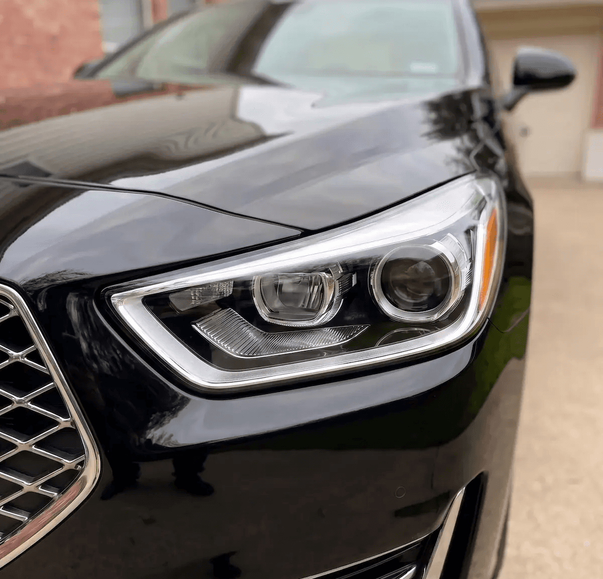 Professional headlight restoration on a black Genesis G90 in Houston, removing oxidation and yellowing for a factory-new finish.