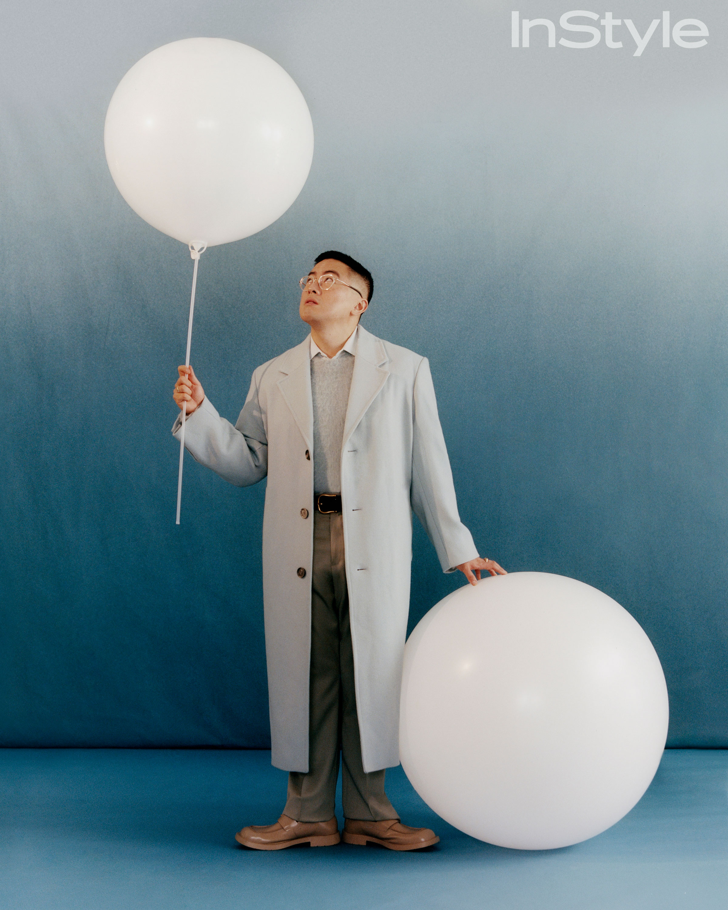 Bowen Yang with oversized white balloons for InStyle