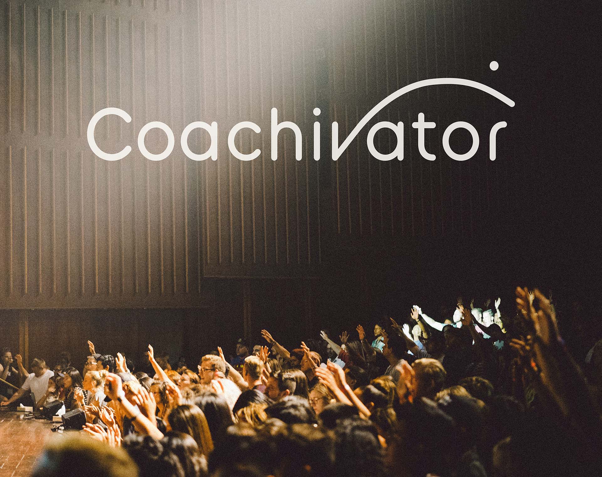 Coachivator Logo set overlaid on a photograph of a coaching presentation