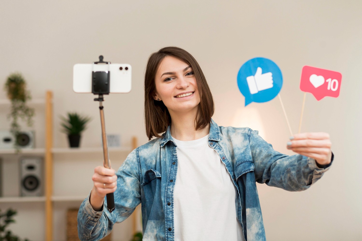 A woman raises a selfie stick, surrounded by various social media icons, capturing a moment for her online presence