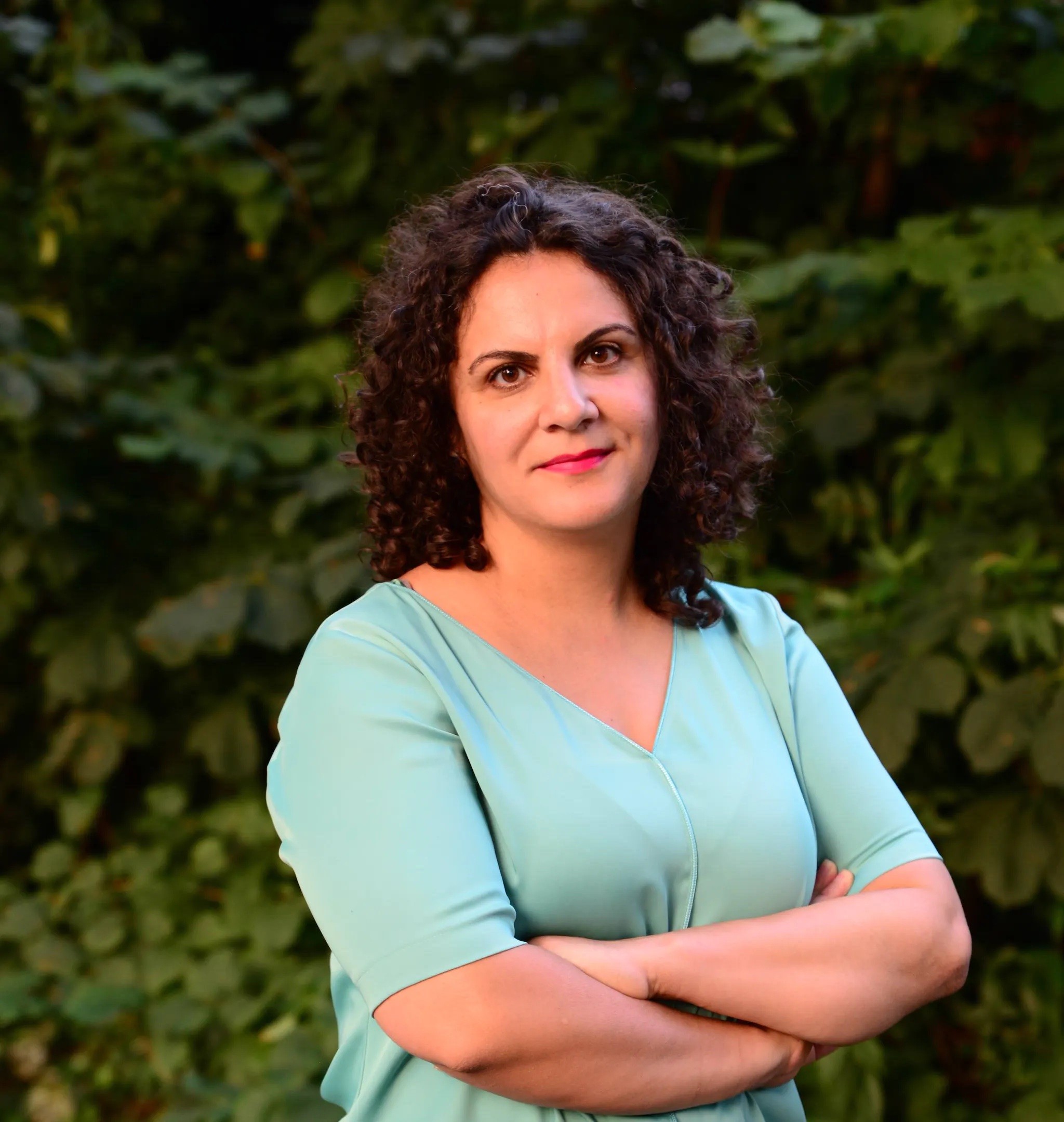A smiling woman in a grey blazer indoors.