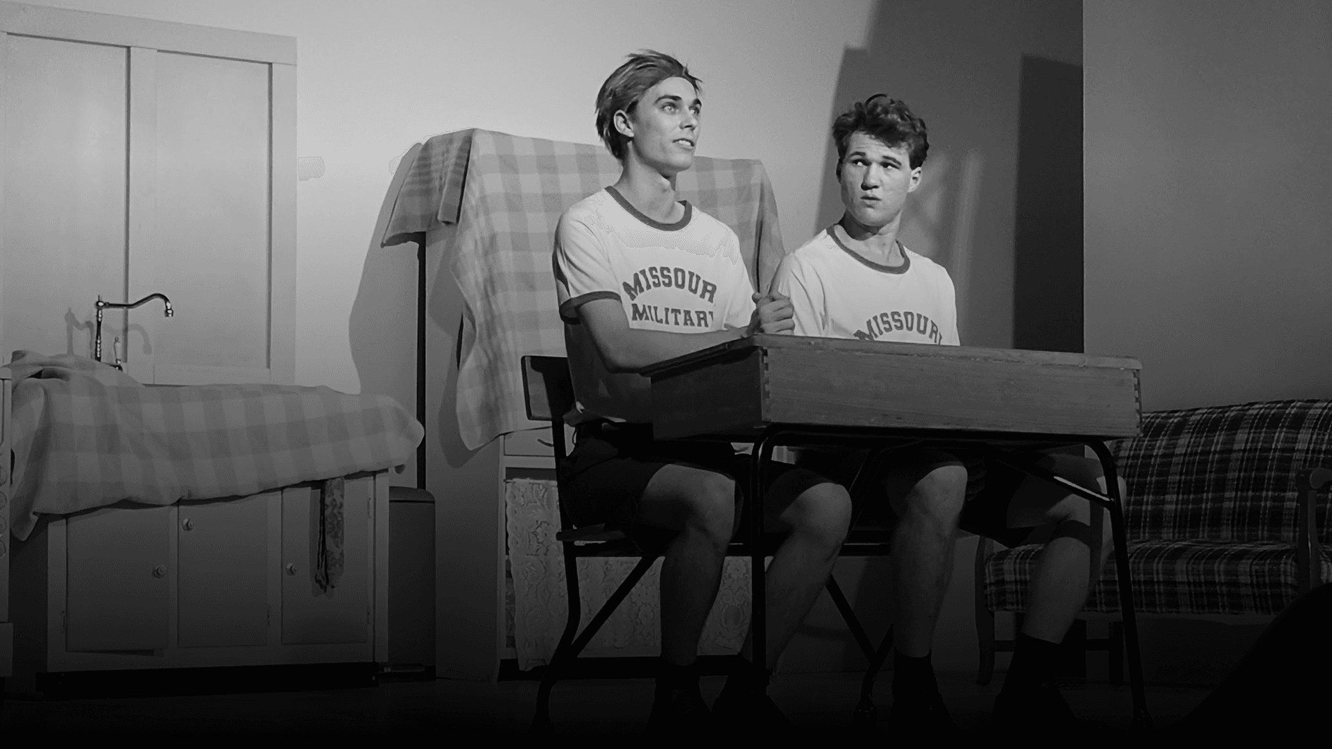 Two actors sitting on a stage in front of an audience