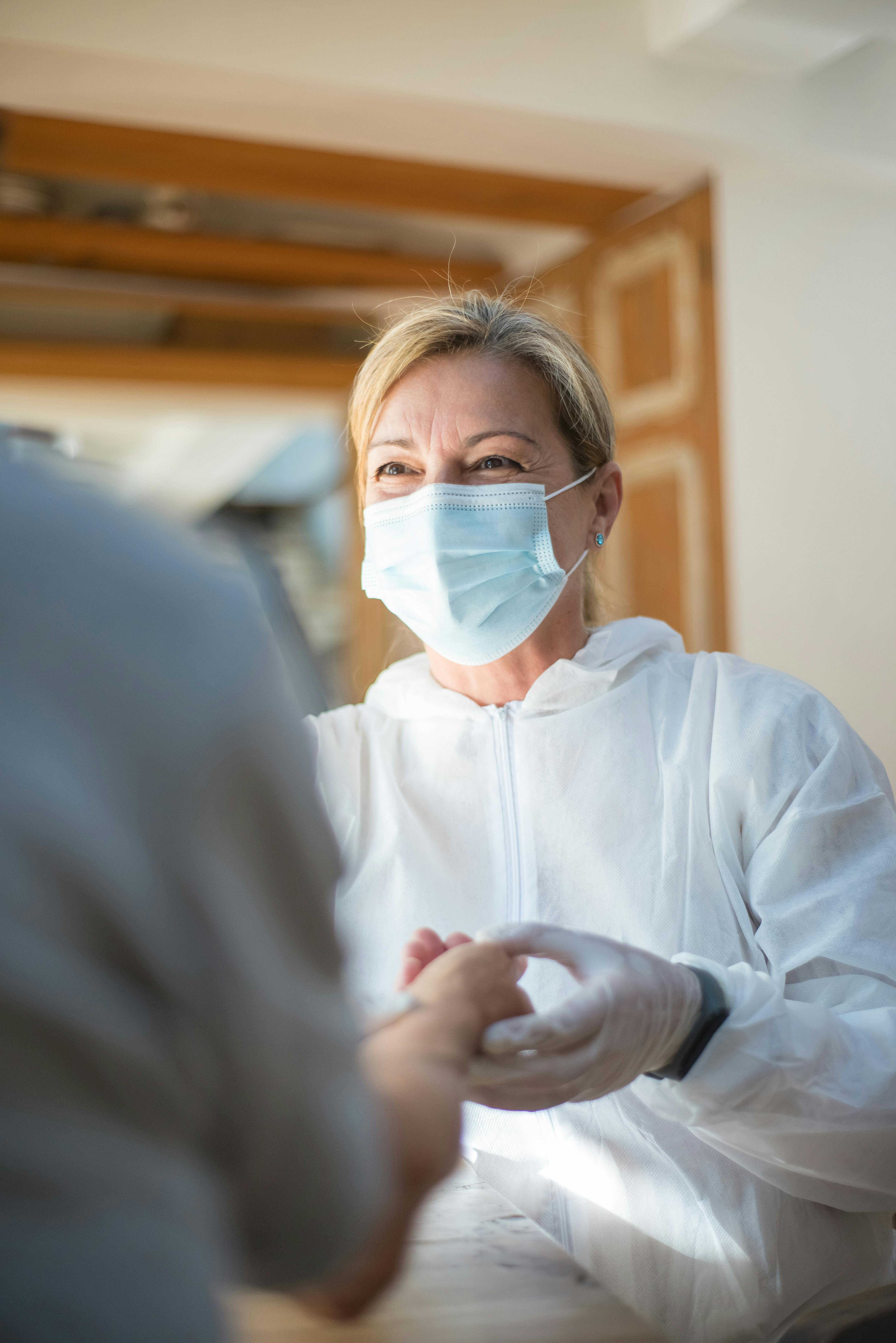 Vrouw met krullend haar, gekleed in een gestreept shirt en een bruine cardigan, bekijkt een tablet met informatie over RI&E dossieracties.