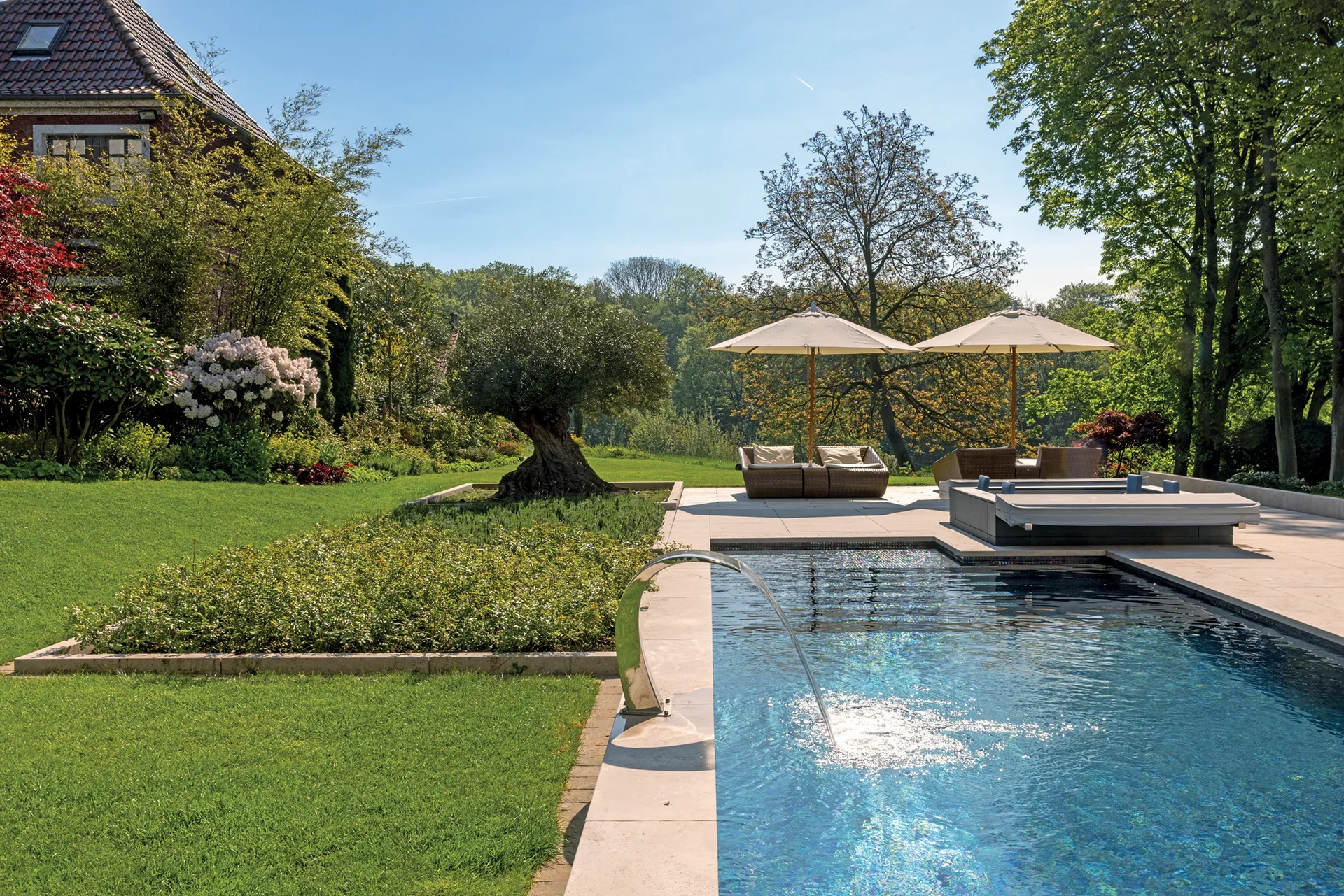 Lush gardens with poolside, sun loungers, and parasols