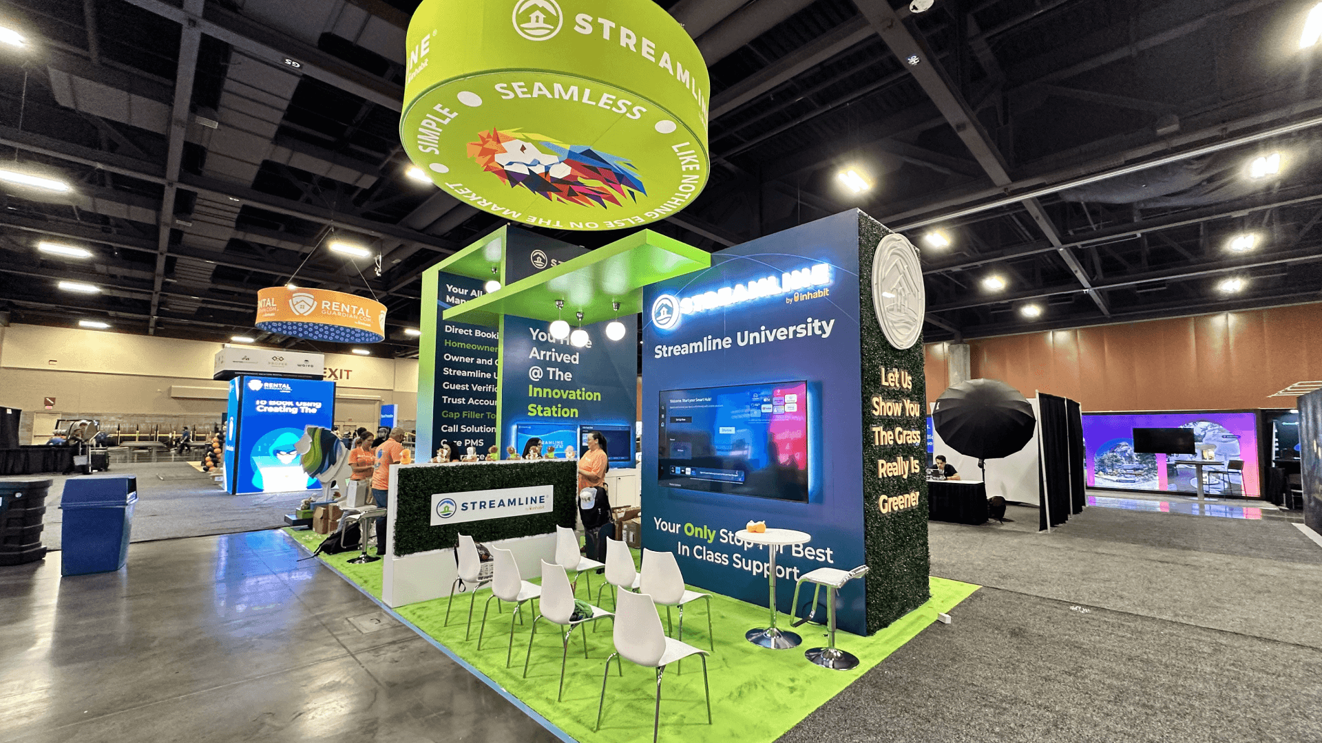 Streamline VRMA 2024 20x30 property technology demo booth with hanging sign, screen presentation, seating area, branded graphics, and visitor flow