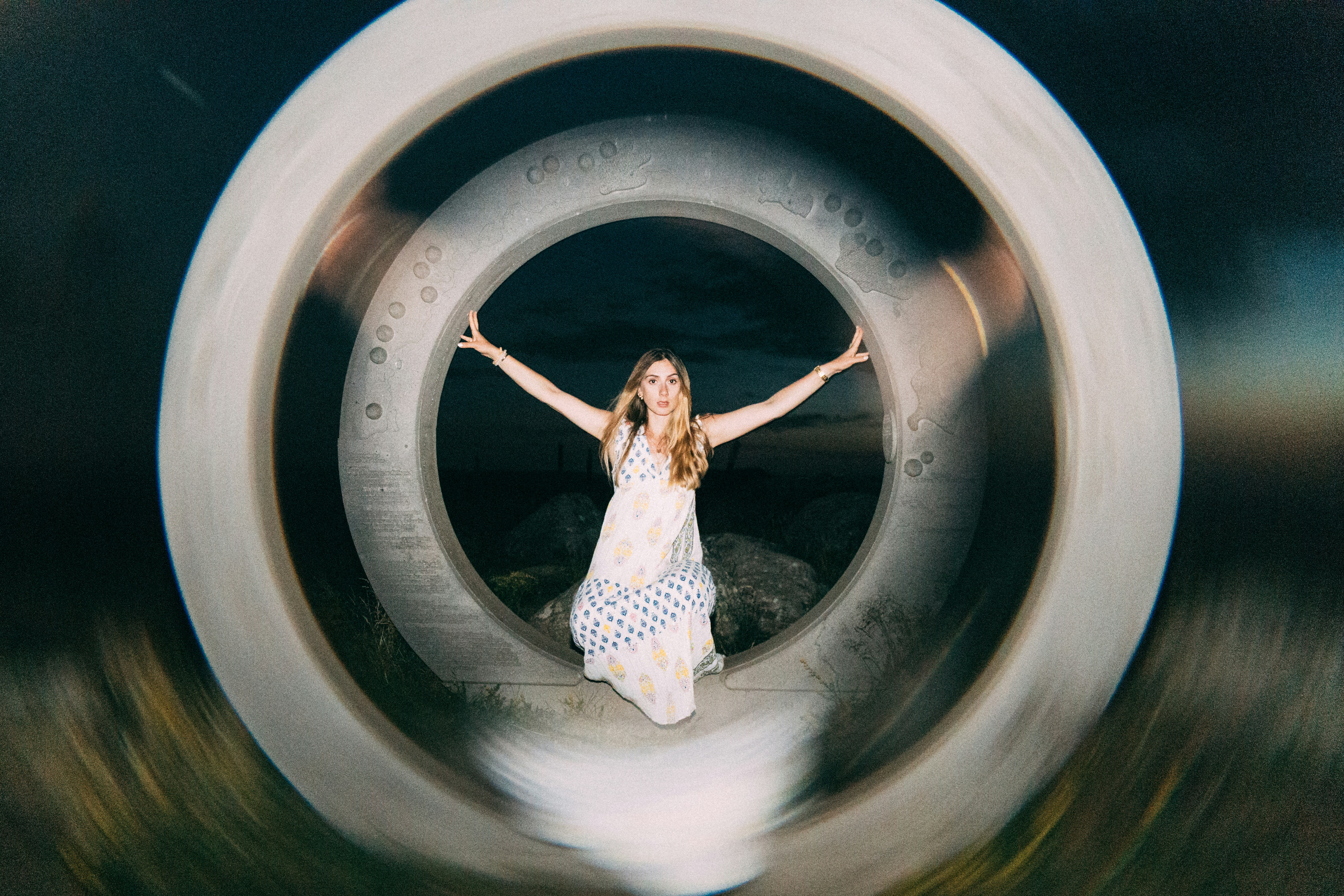 A woman poses inside circular structures with arms out.