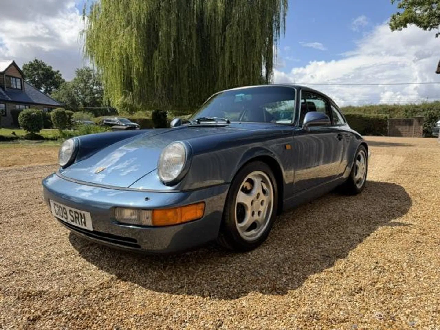 Baltic Blue Porsche 964 C4 Coupé front three-quarter view on gravel driveway