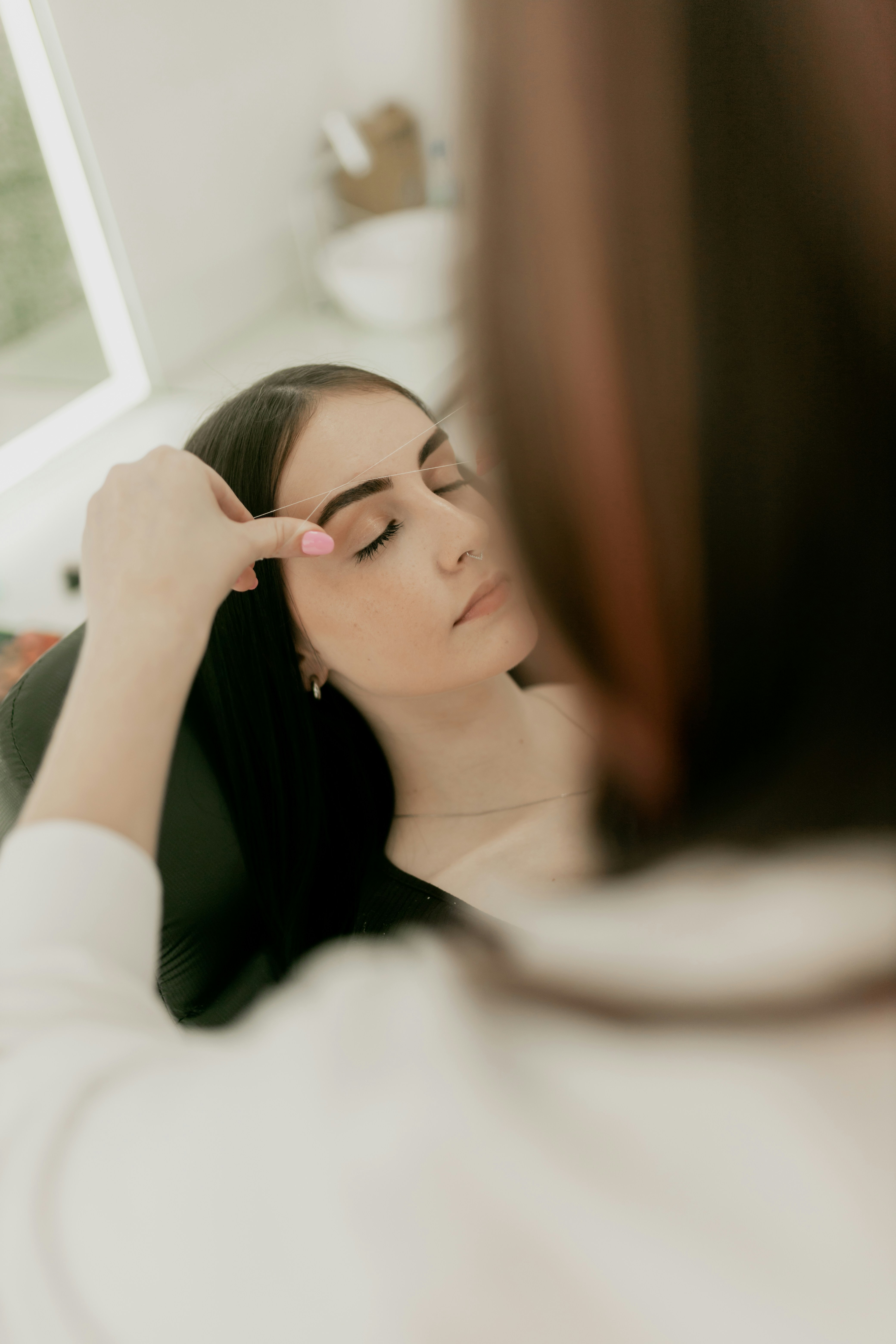 A woman is brushing her hair in front of a mirror