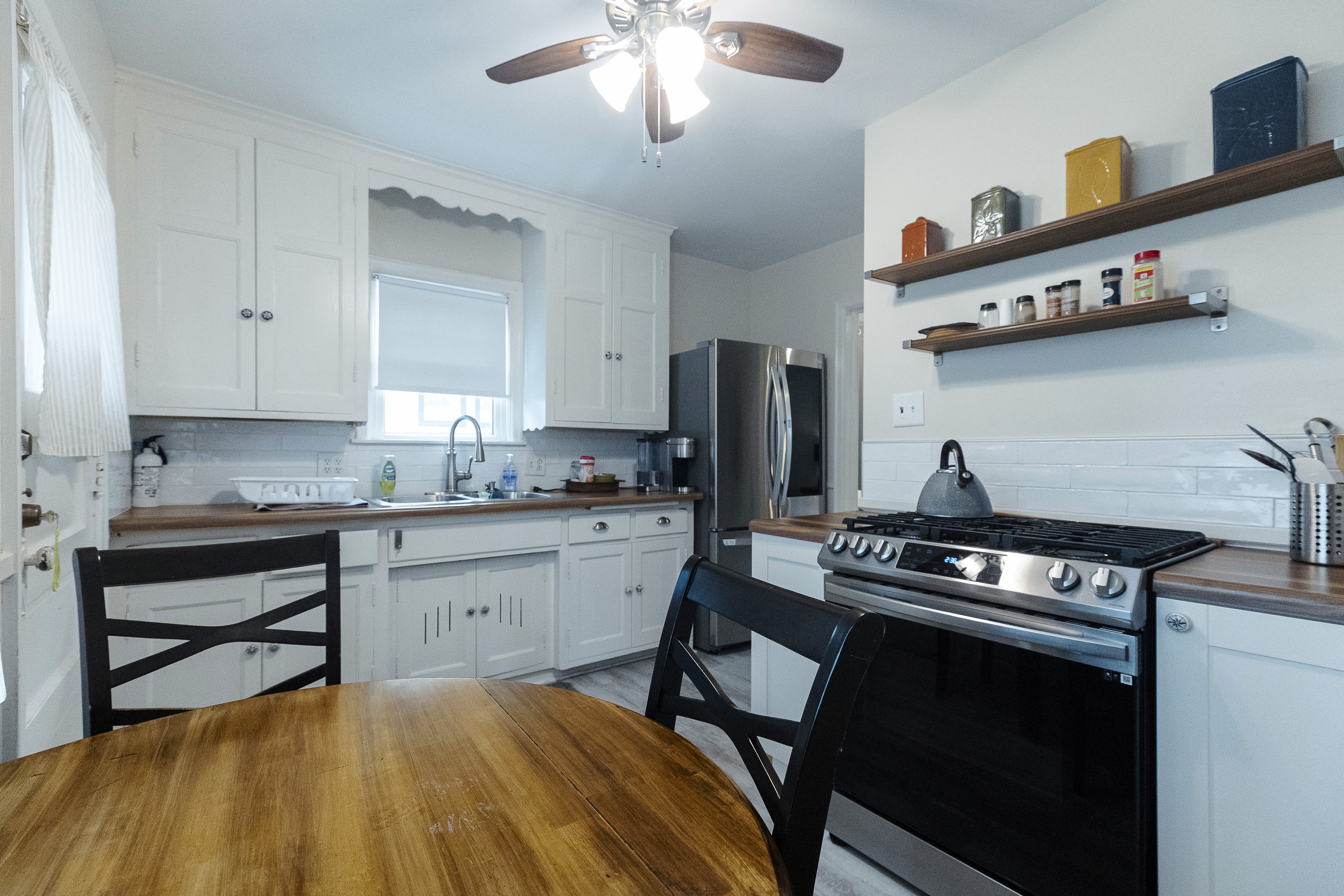 Bright kitchen featuring white cabinets, a gas stove, and a wooden dining table.