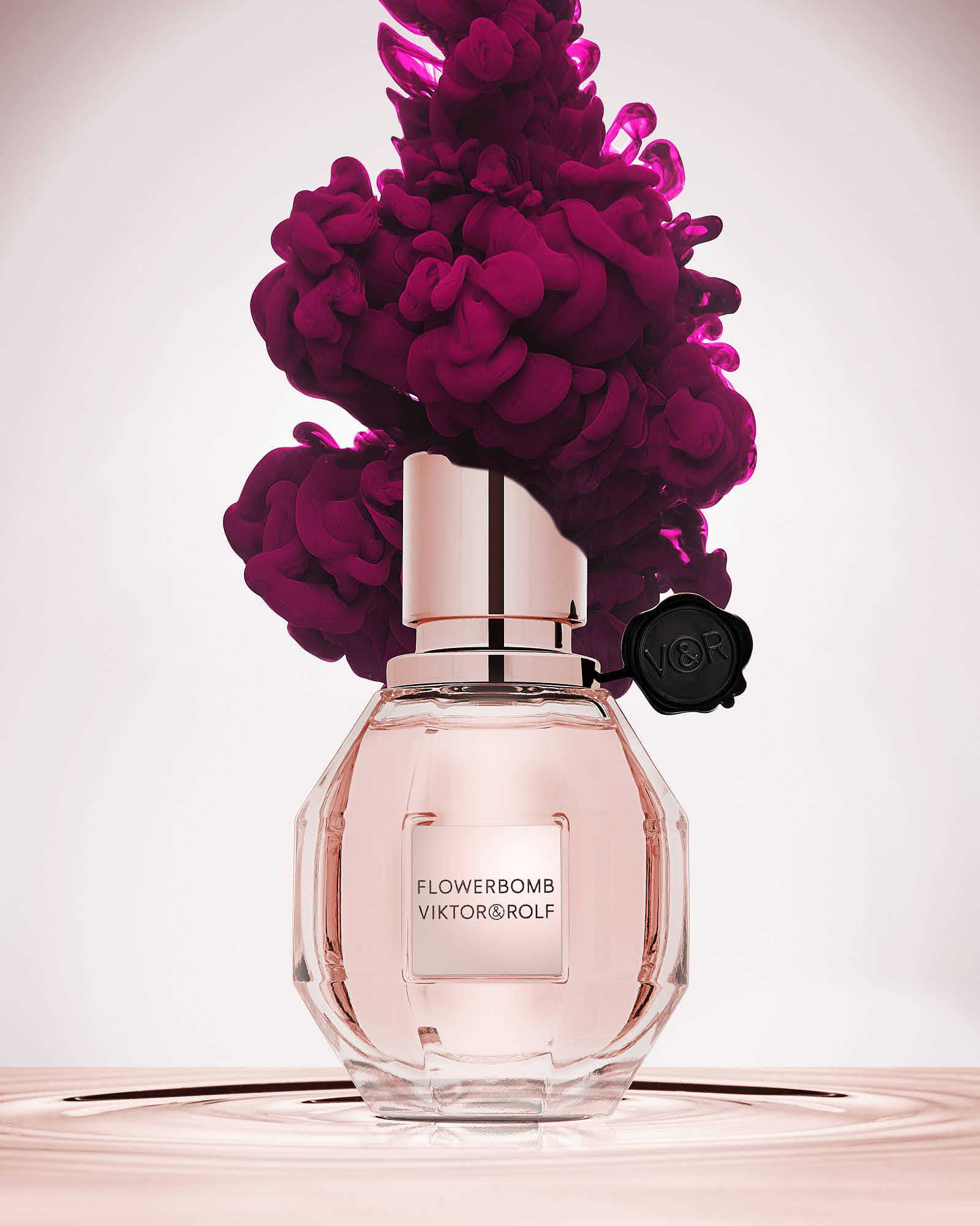 A pink bottle of womens perfume topped with vibrant, fuchsia ink against a light background.