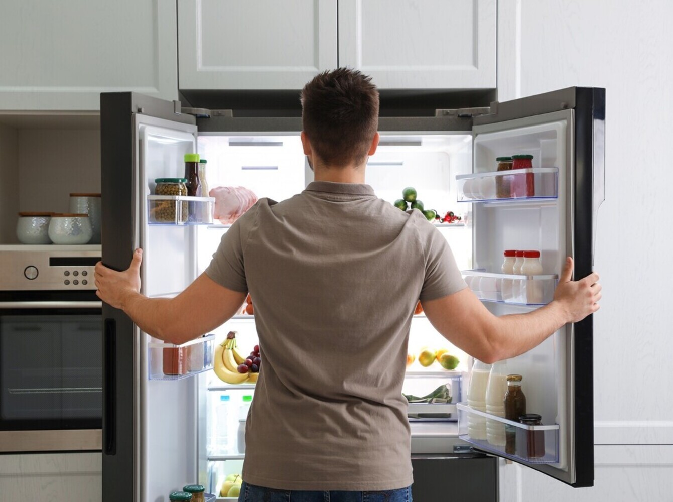 man opening fridge because he’s very hungry after trying to lose weight swimming