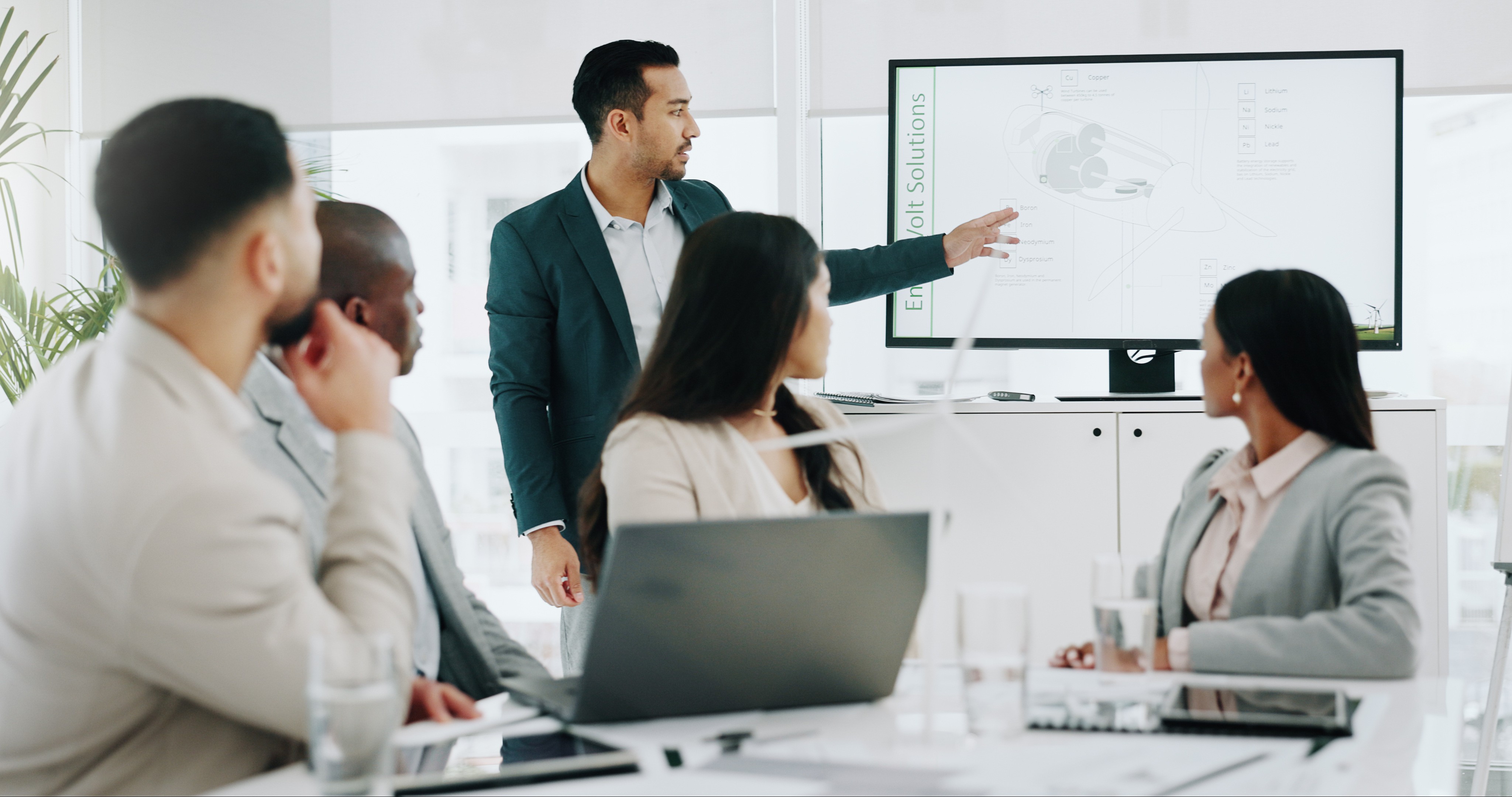 A business professional presenting data on a screen to a group in a conference room.