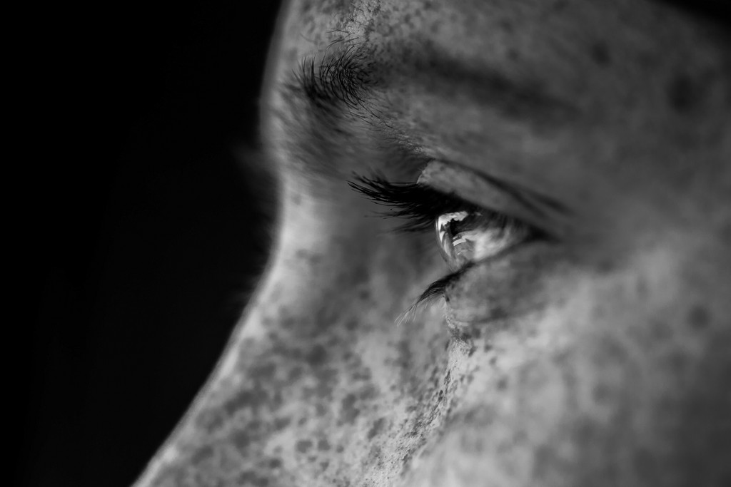 Closeup black white image zoomed in of a woman with freckles eye from the side