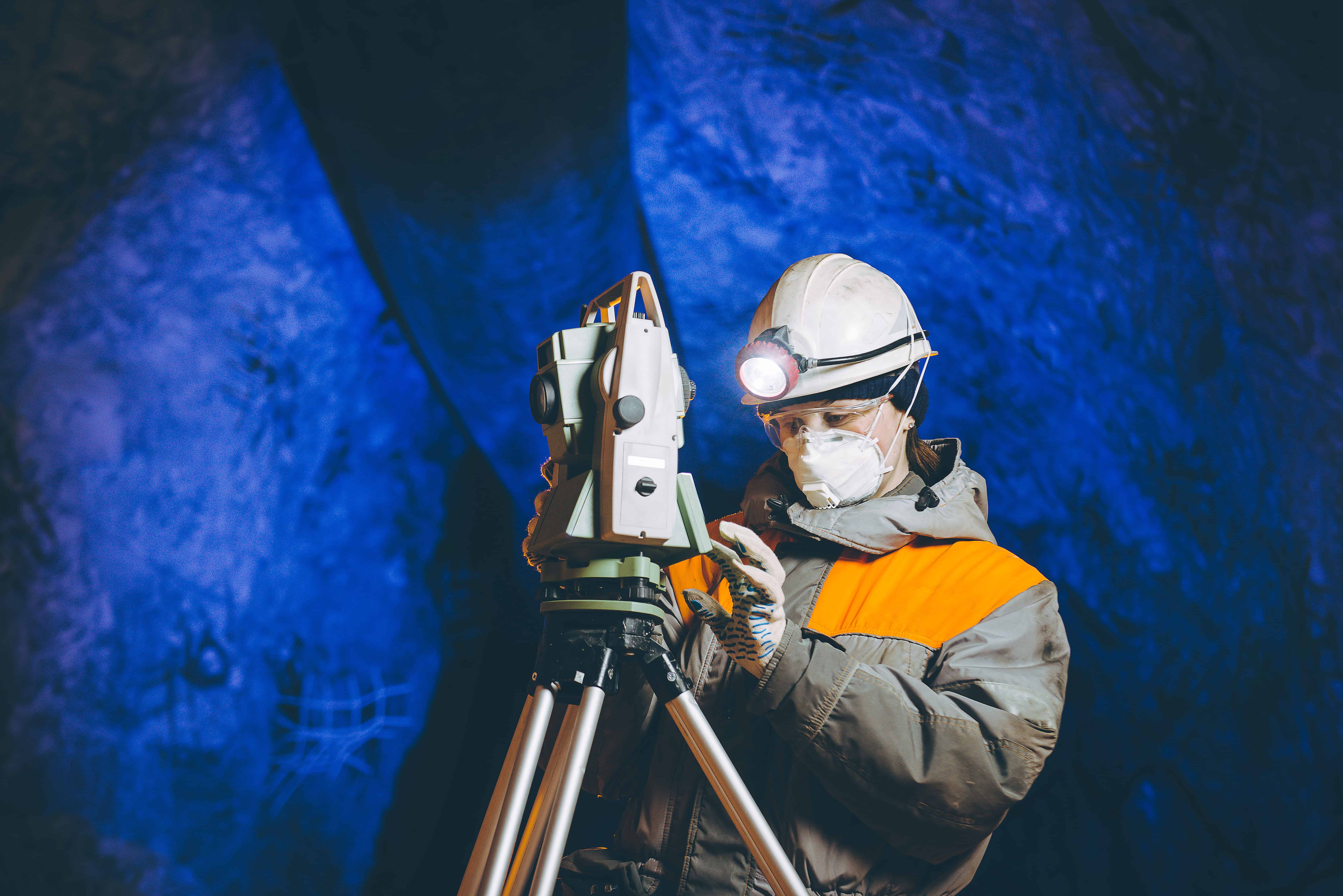 Female geologist in an underground mine setting up surveying equipment and managing her wellbeing