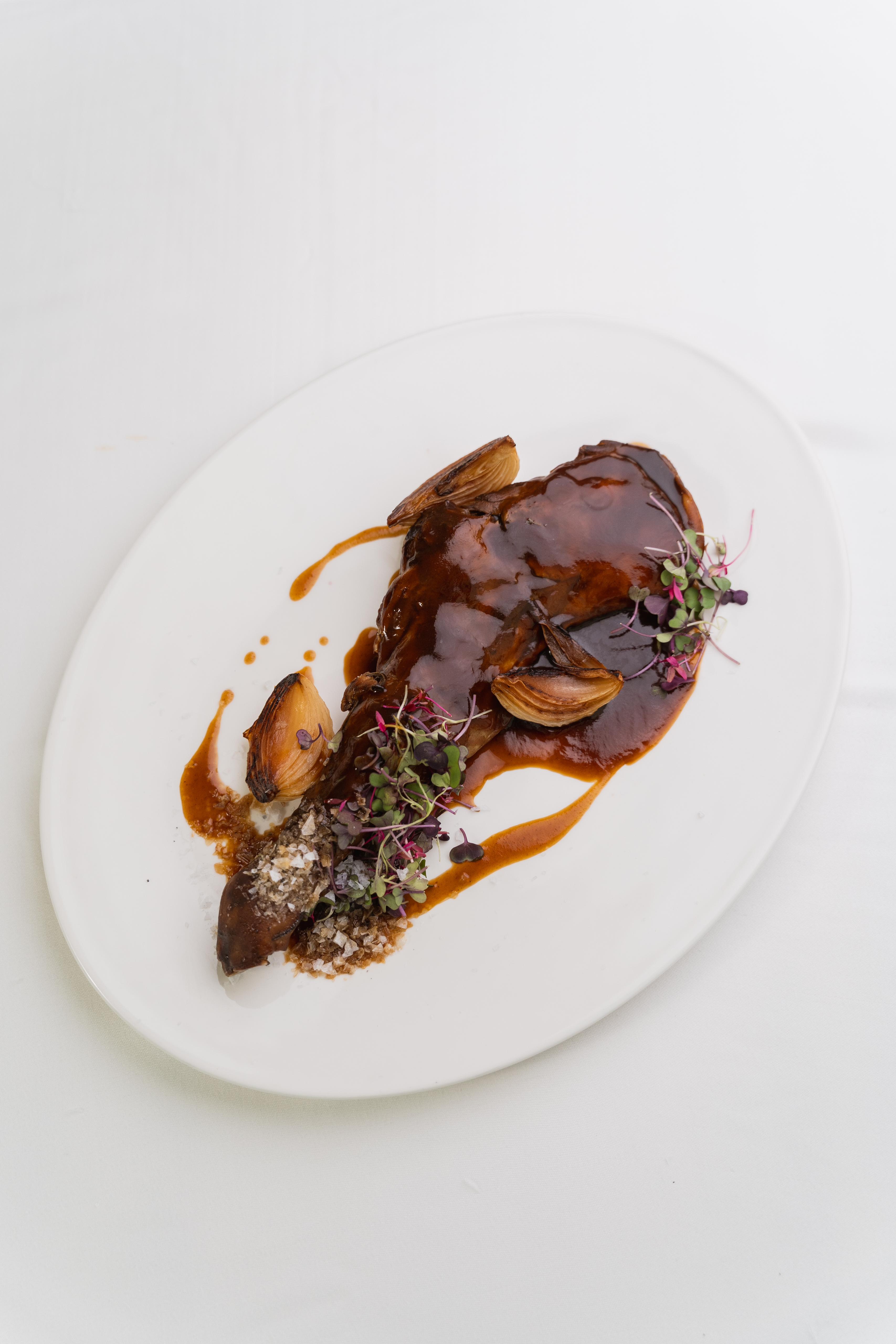 A winding road cuts through rocky terrain, surrounded by patches of green grass and illuminated by sunlight.