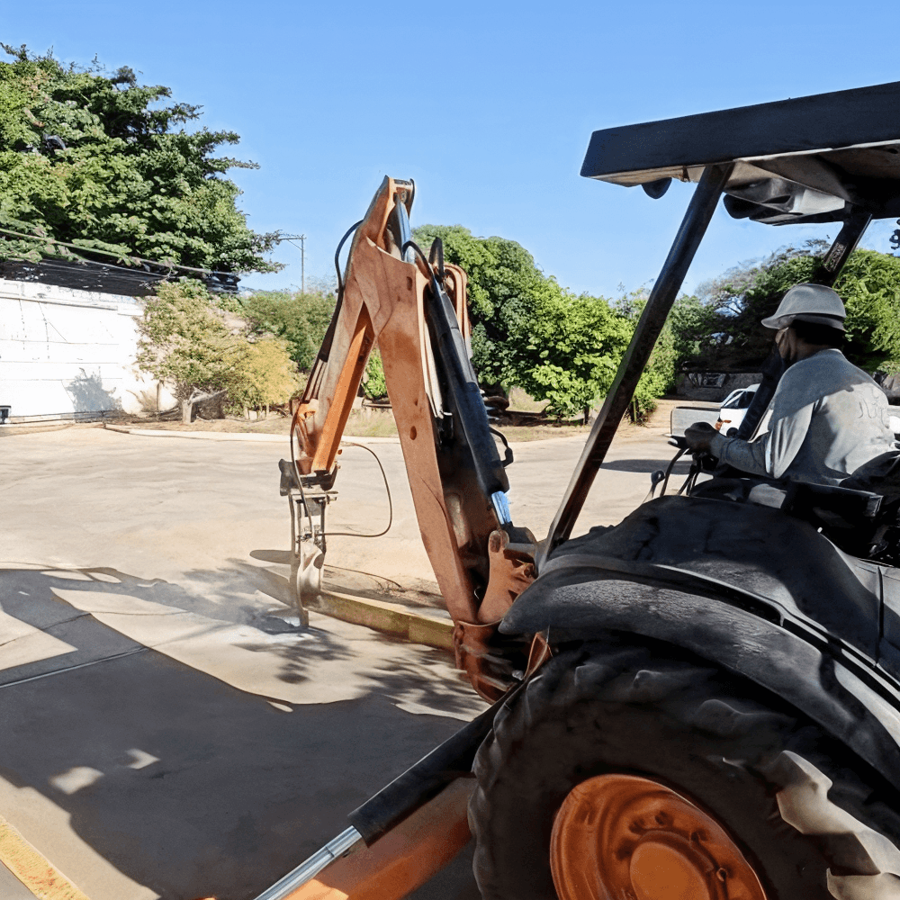 yellow excavator beside brown brick wall