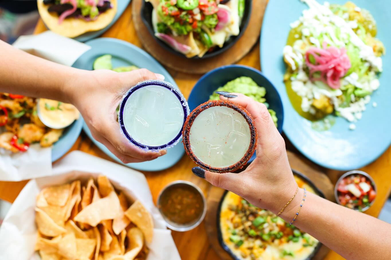 Guests cheering with glasses of margaritas at Blue Plate Taco, capturing the lively, celebratory atmosphere of this Santa Monica favorite."